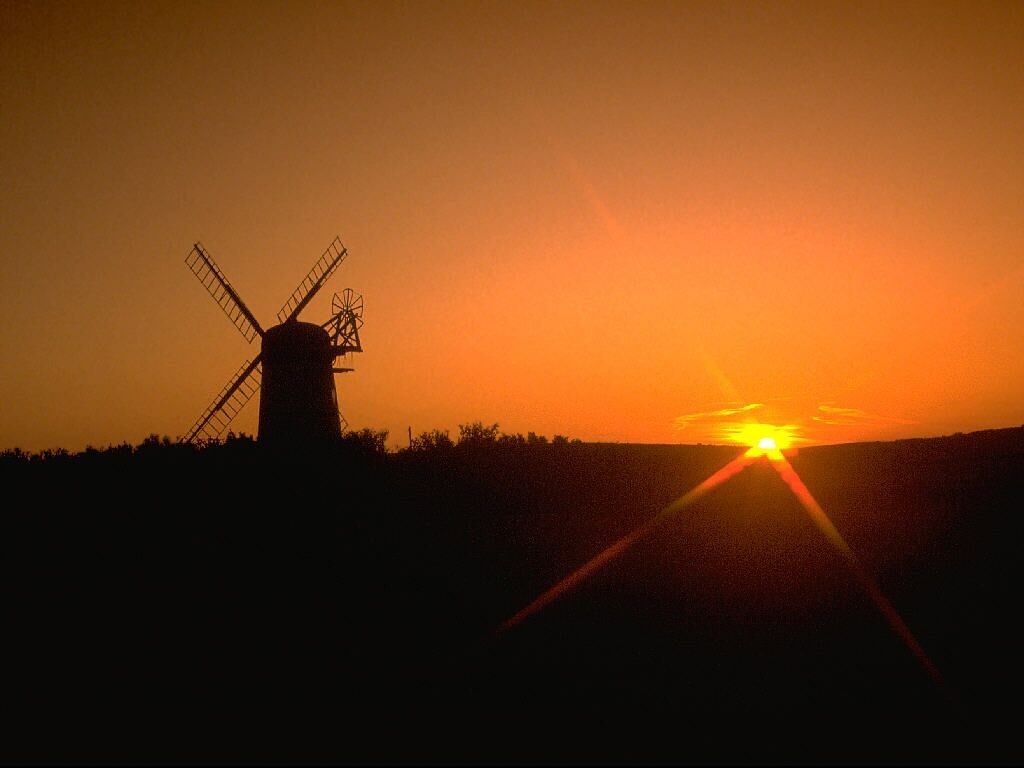 Silhouette of a windmill against a sunset sky HD Wallpaper