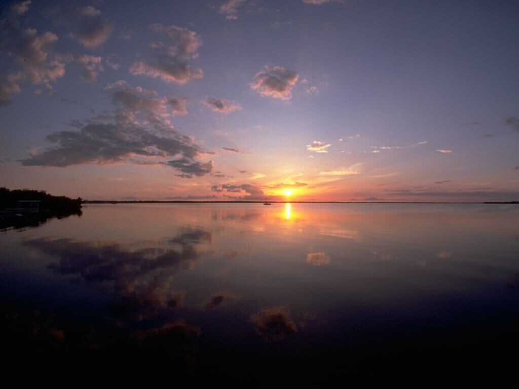 Sunset over a calm body of water with reflections HD Wallpaper