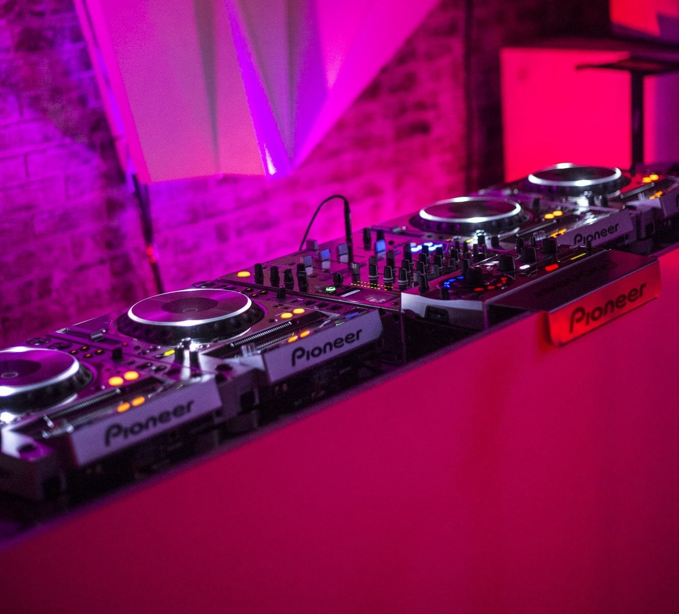 Pioneer DJ turntables and mixer setup with pink lighting HD Wallpaper