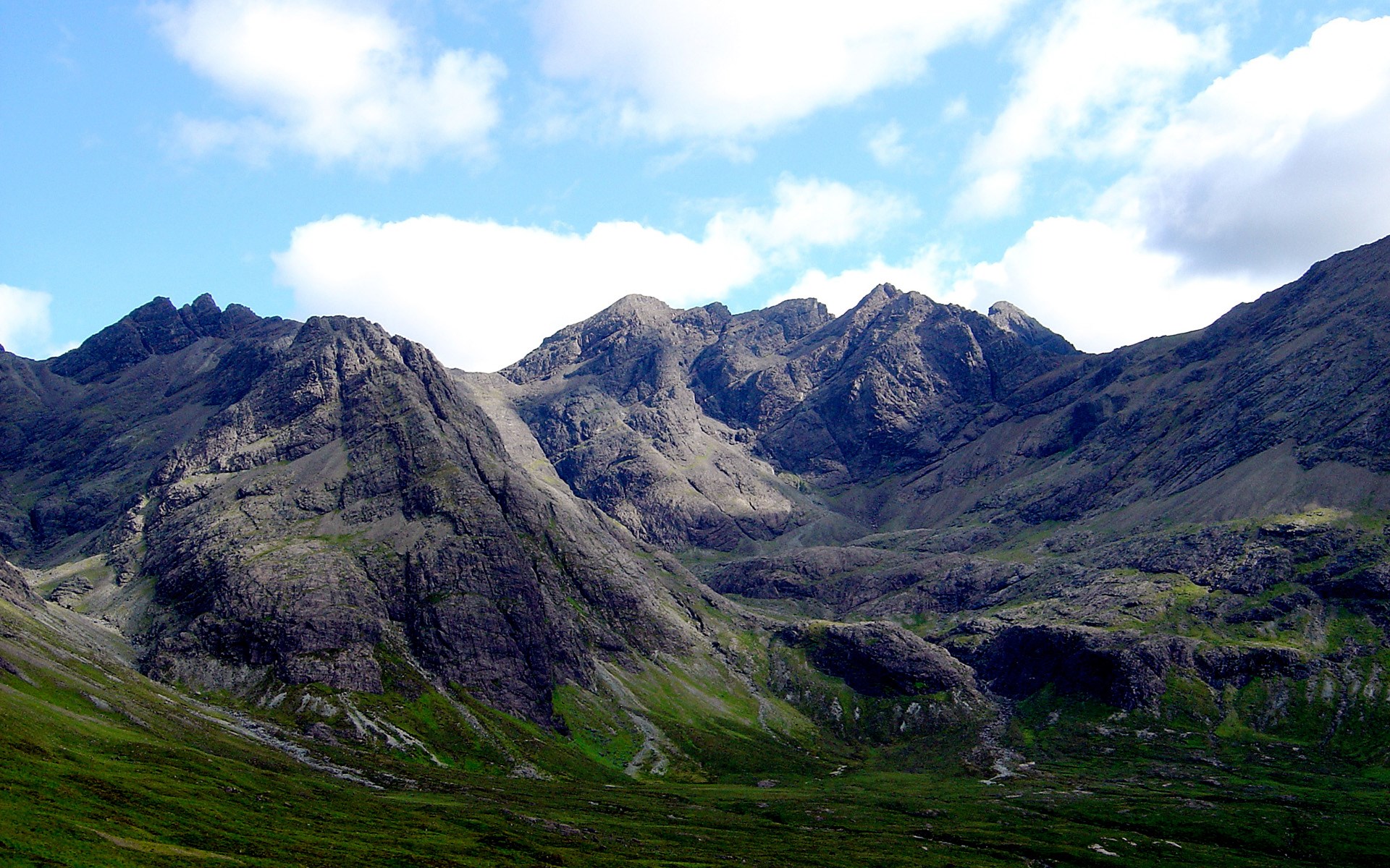 Jagged mountains under a cloudy blue sky HD Wallpaper