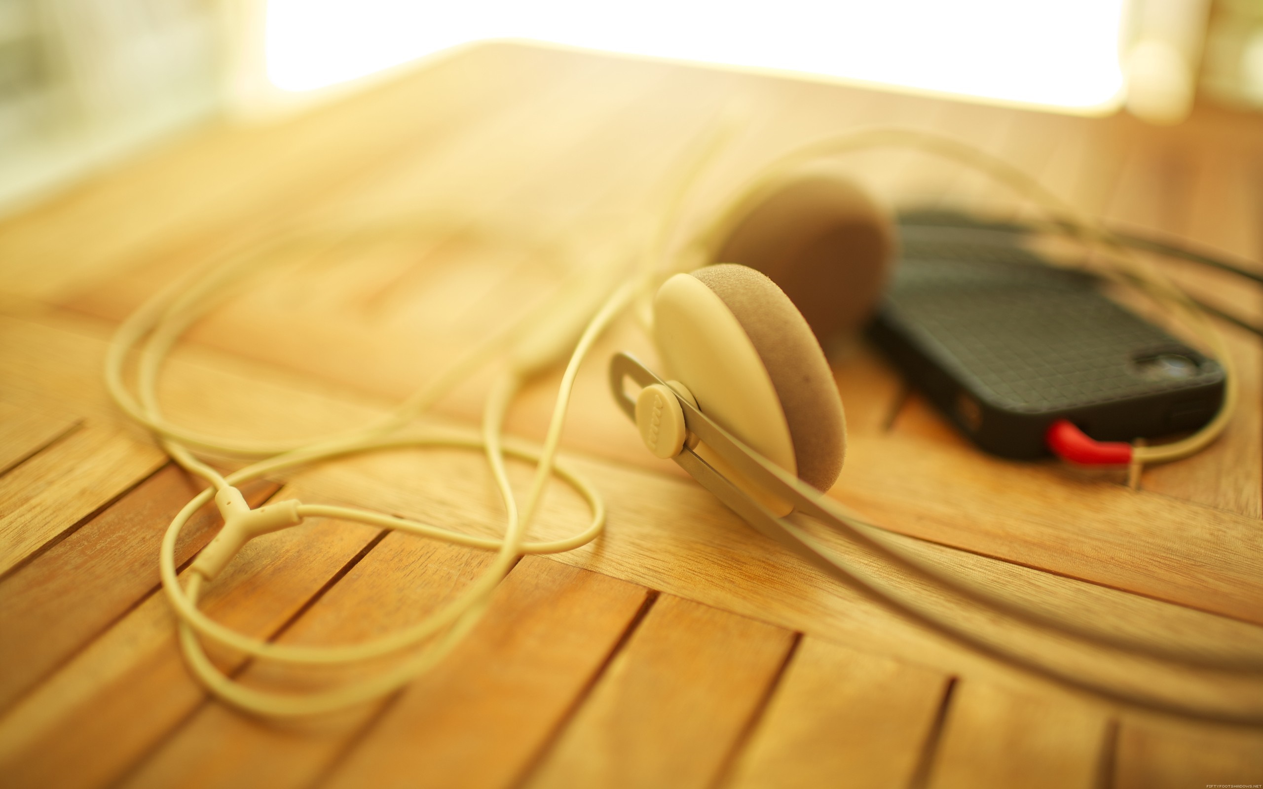 Headphones and smartphone on a wooden table HD Wallpaper