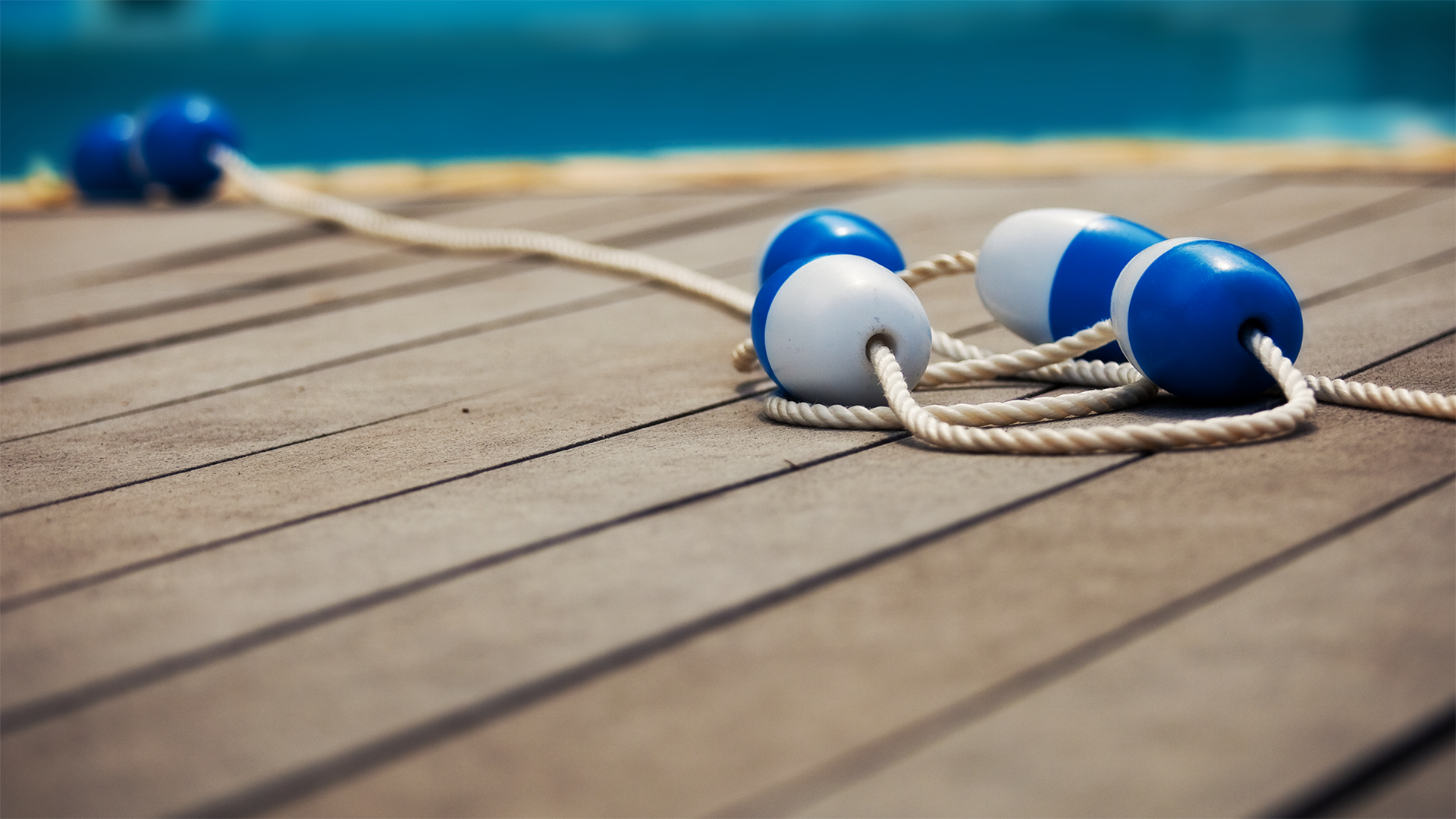 Blue and white buoys on a rope on a wooden deck HD Wallpaper