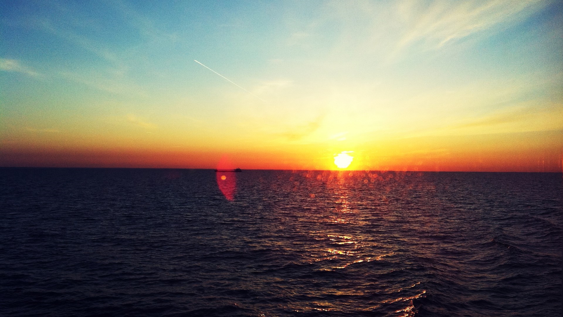 Sunset over the ocean with a ship and contrail HD Wallpaper