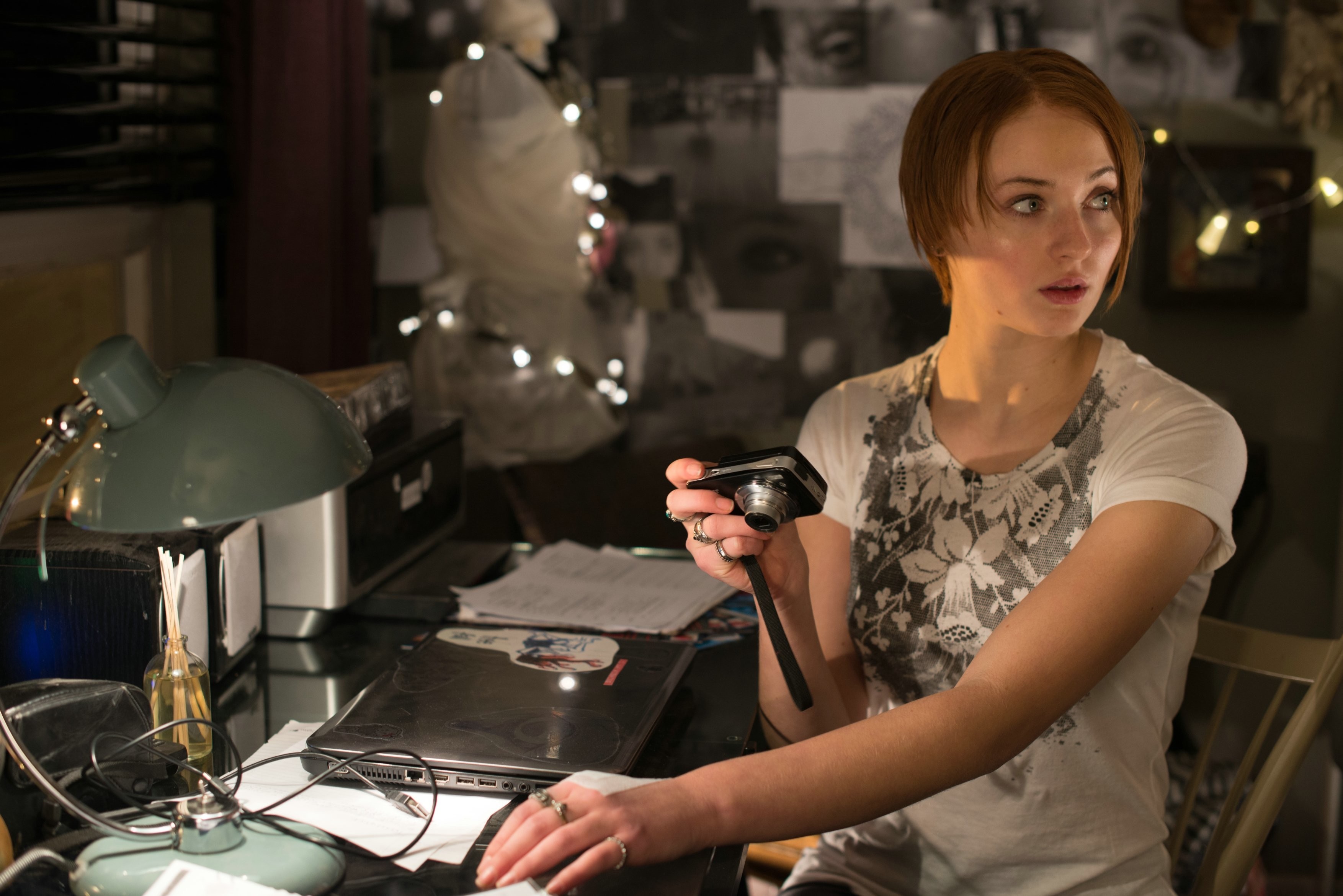 Sophie Turner holding a camera at a desk HD Wallpaper