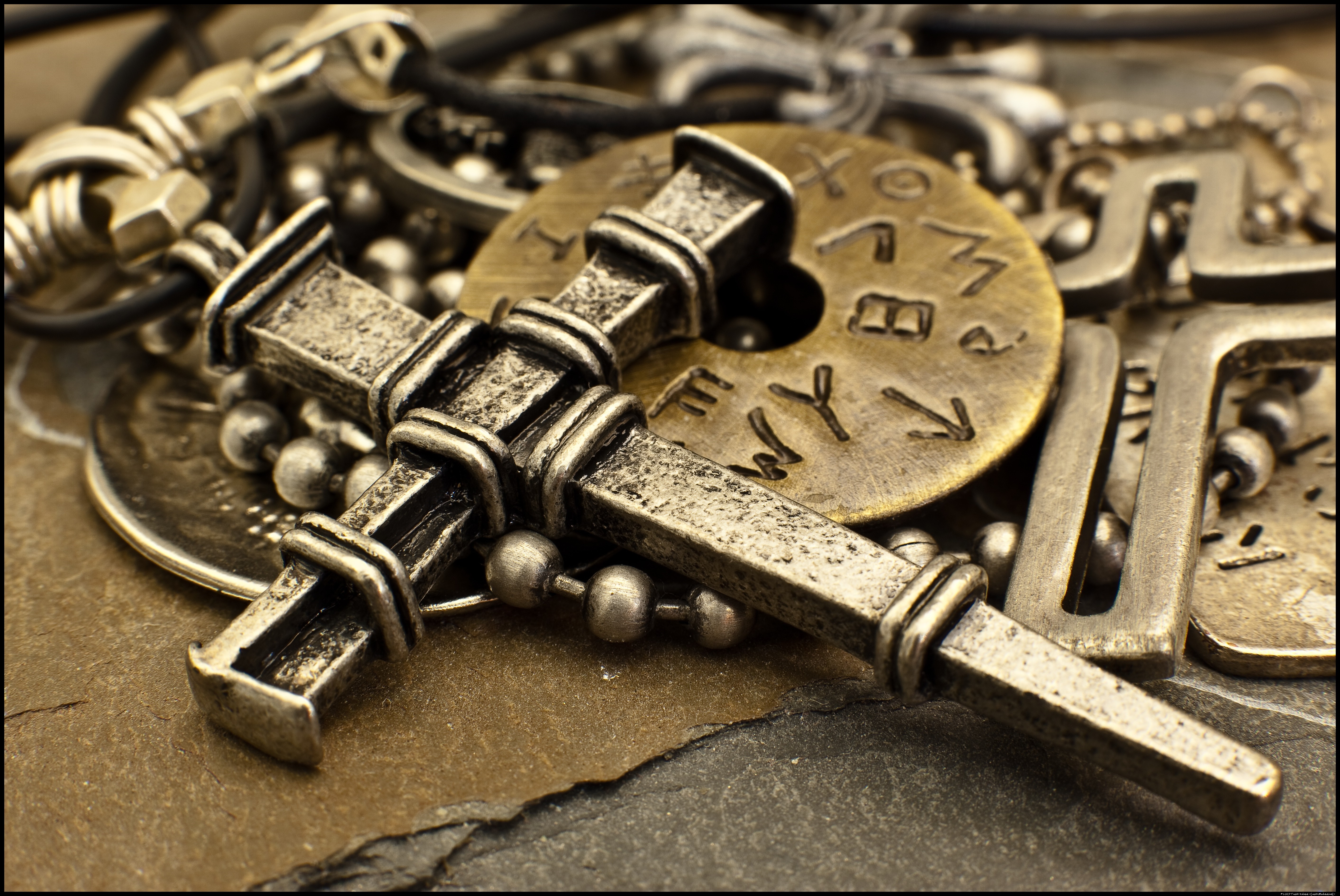 Close-up of a metal cross necklace with ancient symbols HD Wallpaper