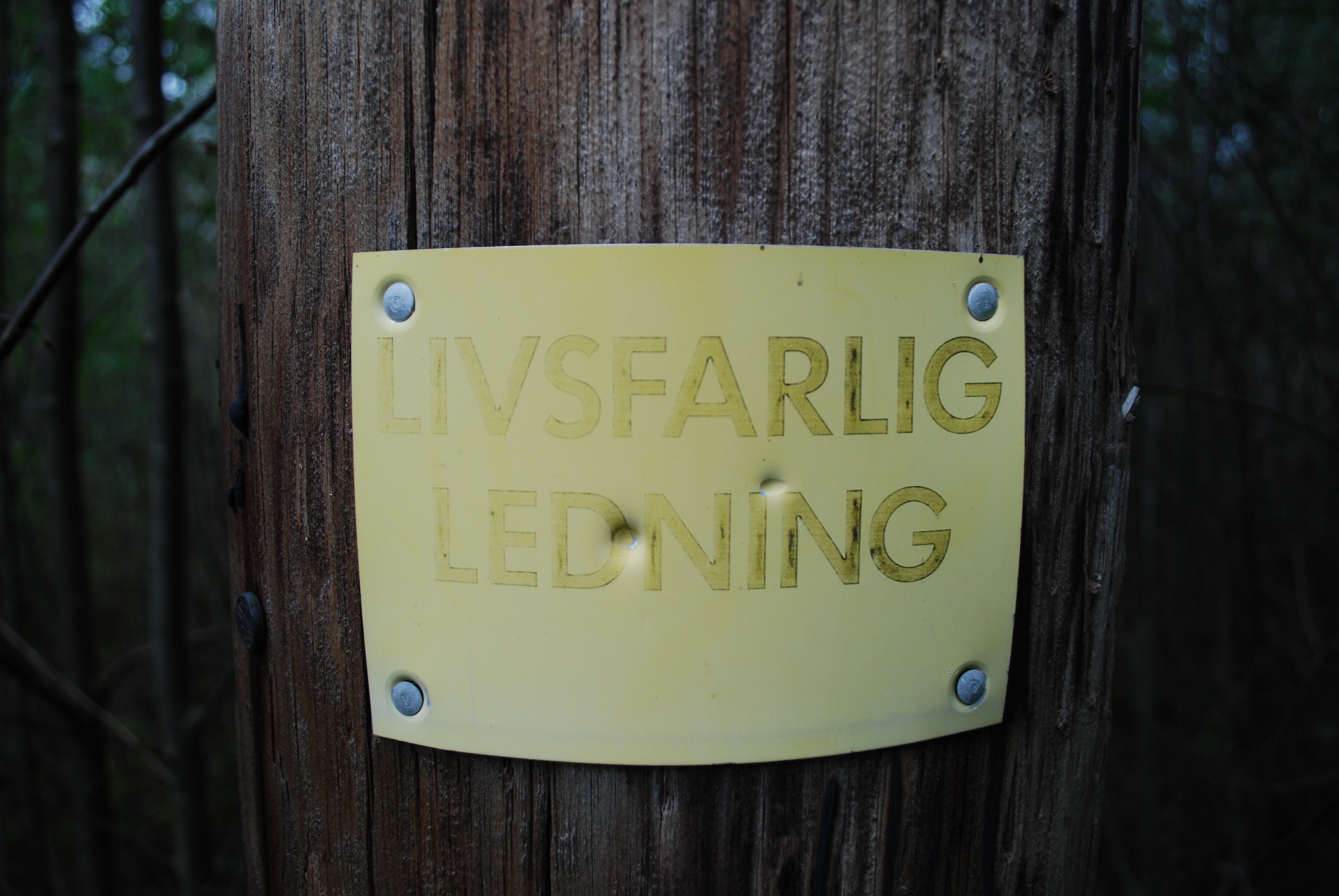 Yellow sign on wooden post with Swedish text HD Wallpaper
