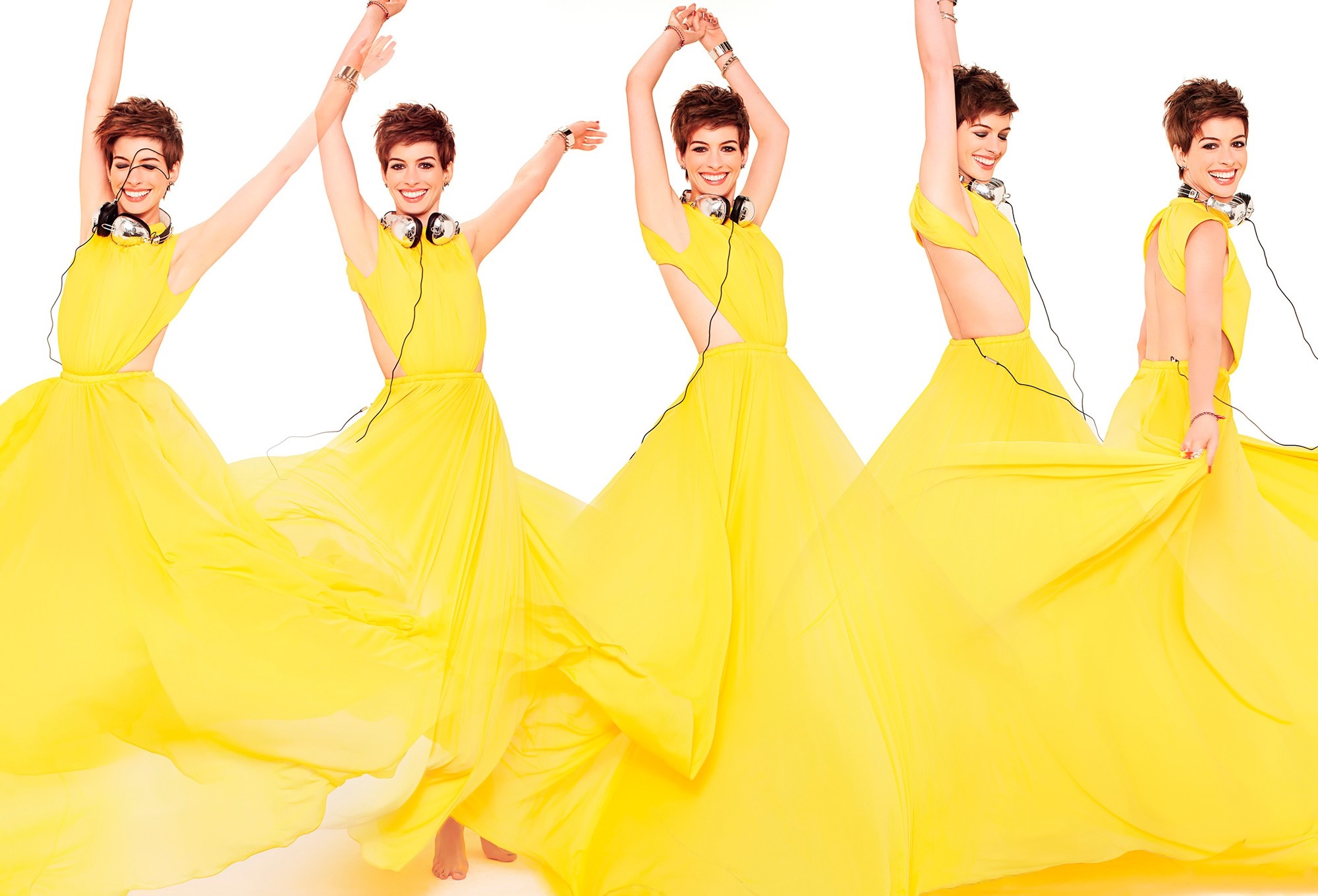 Anne Hathaway in a yellow gown with headphones HD Wallpaper
