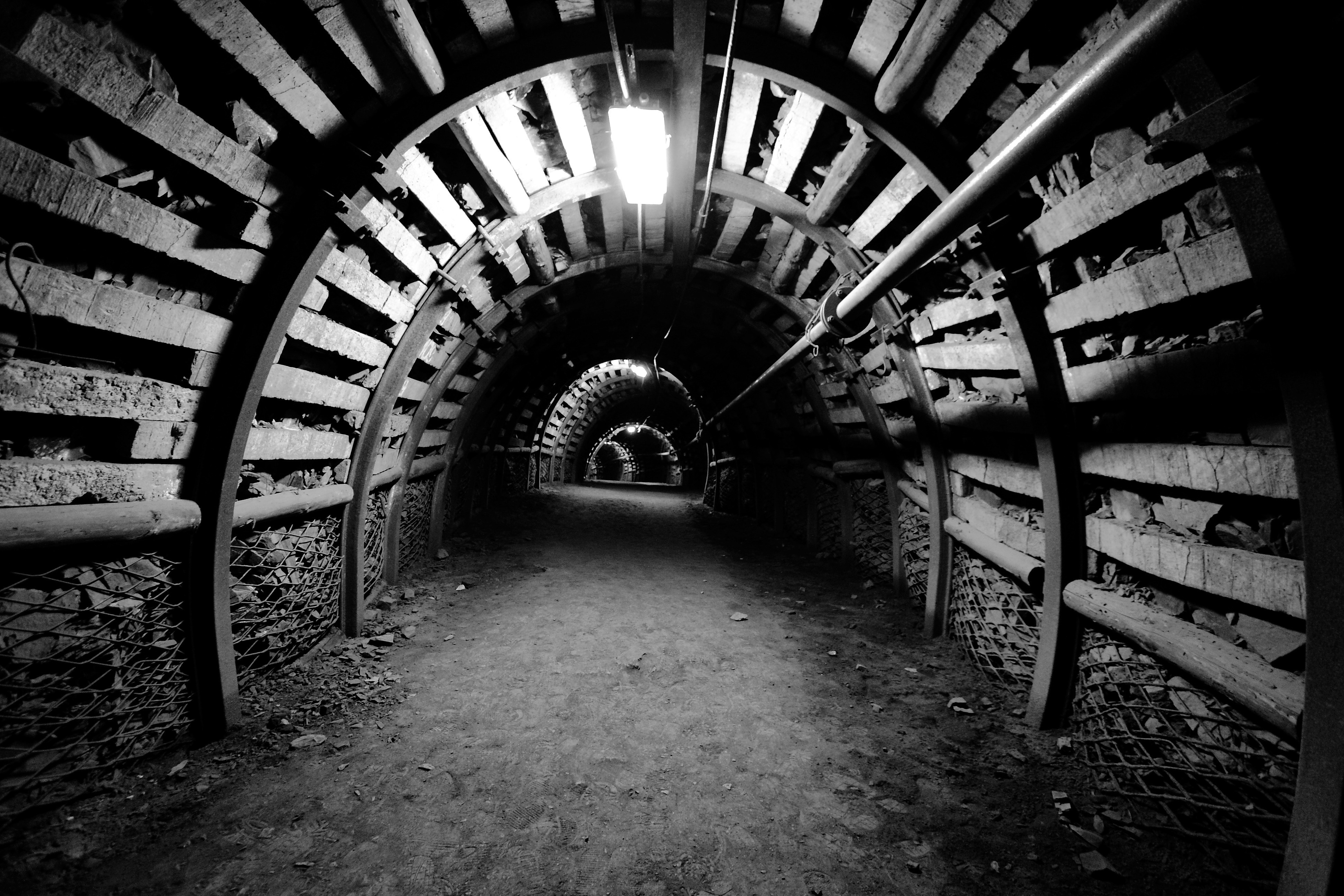 Black and white image of a dark mine tunnel HD Wallpaper