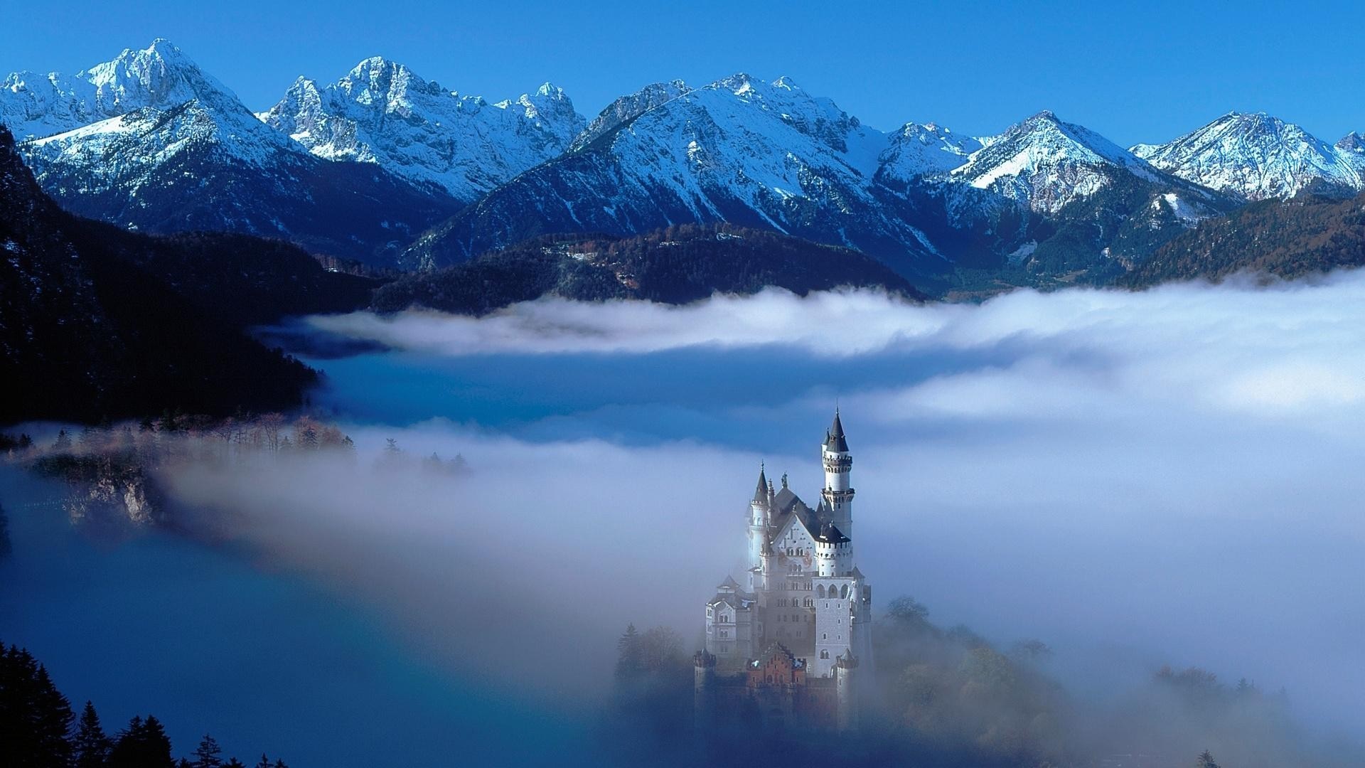 Neuschwanstein Castle in the Alps with Fog and Snow-Capped Mountains HD Wallpaper