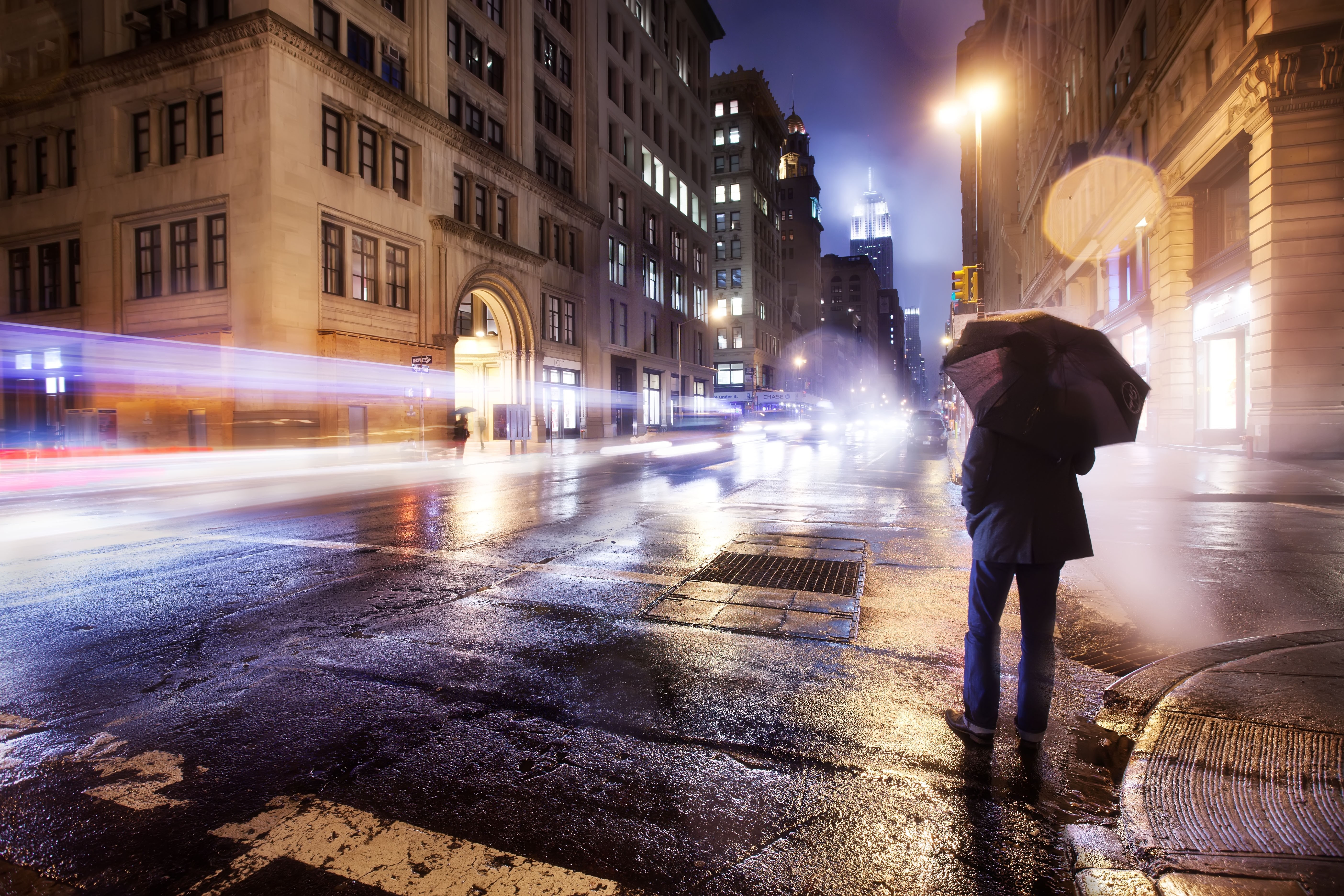 City street at night with a person holding an umbrella HD Wallpaper