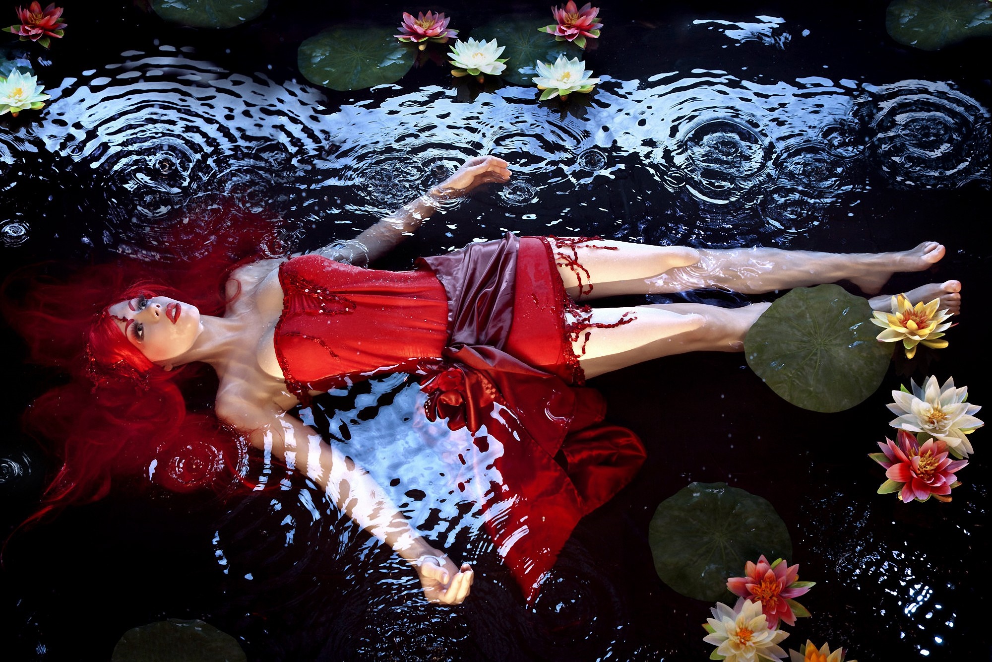 Woman in Red Dress Floating in Water with Lilies HD Wallpaper