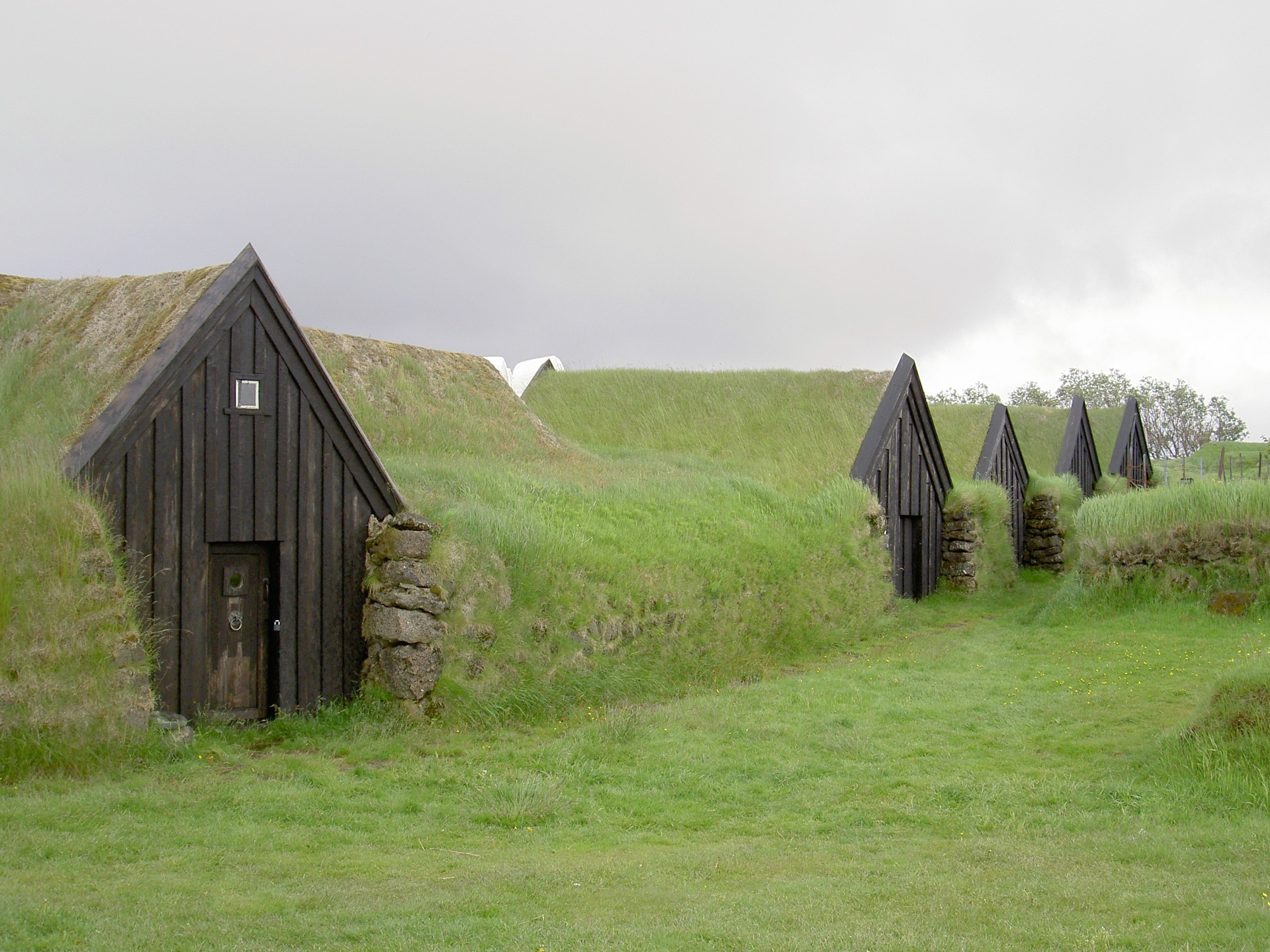 Turf-roofed buildings in a grassy landscape in Iceland HD Wallpaper