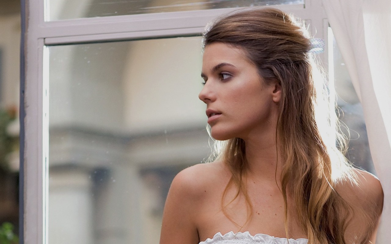 Woman with long brown hair by a window HD Wallpaper