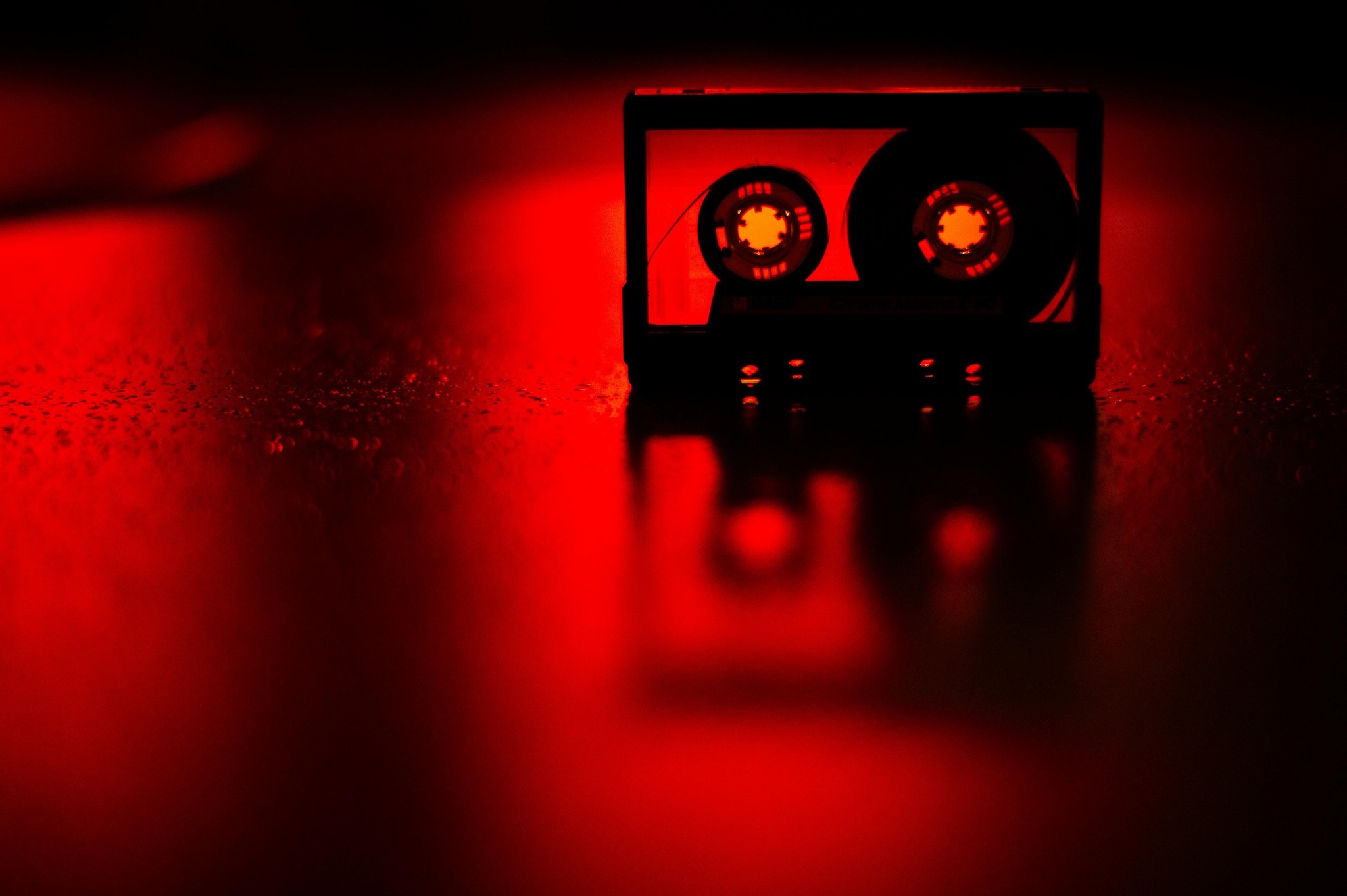 Red cassette tape with glowing spools in darkness HD Wallpaper