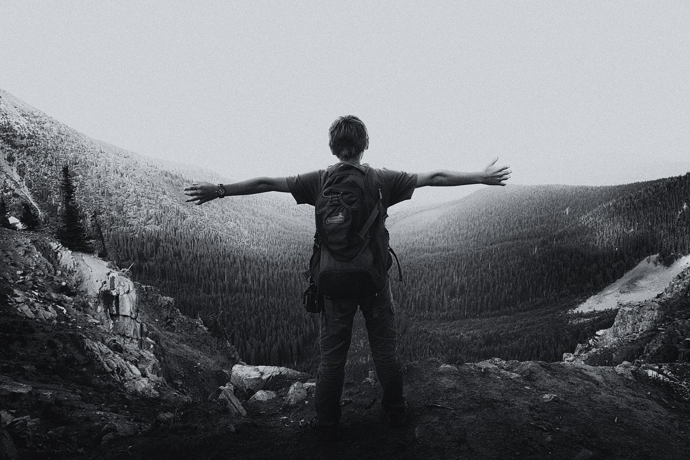 Person with backpack on mountain overlooking forest HD Wallpaper