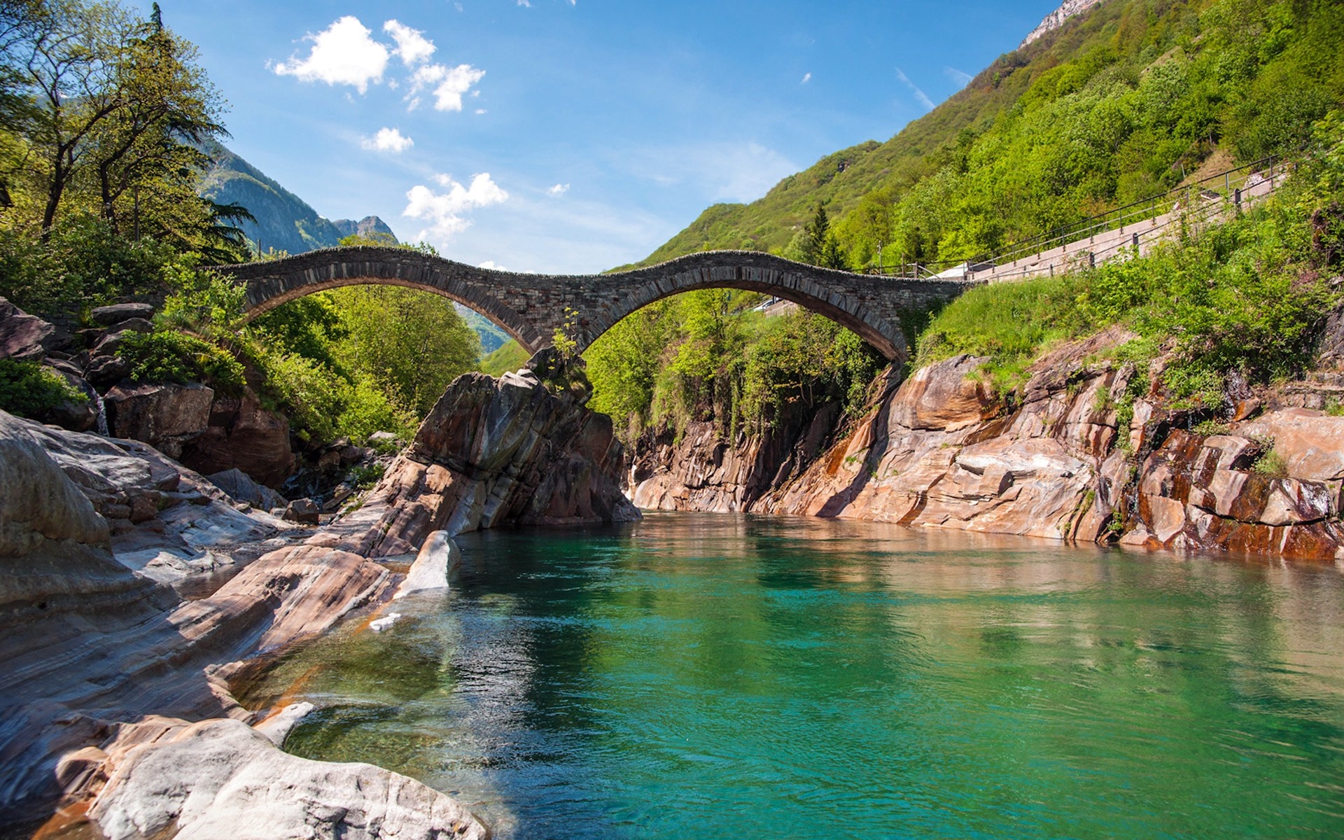 Stone bridge over a turquoise river in a green valley HD Wallpaper