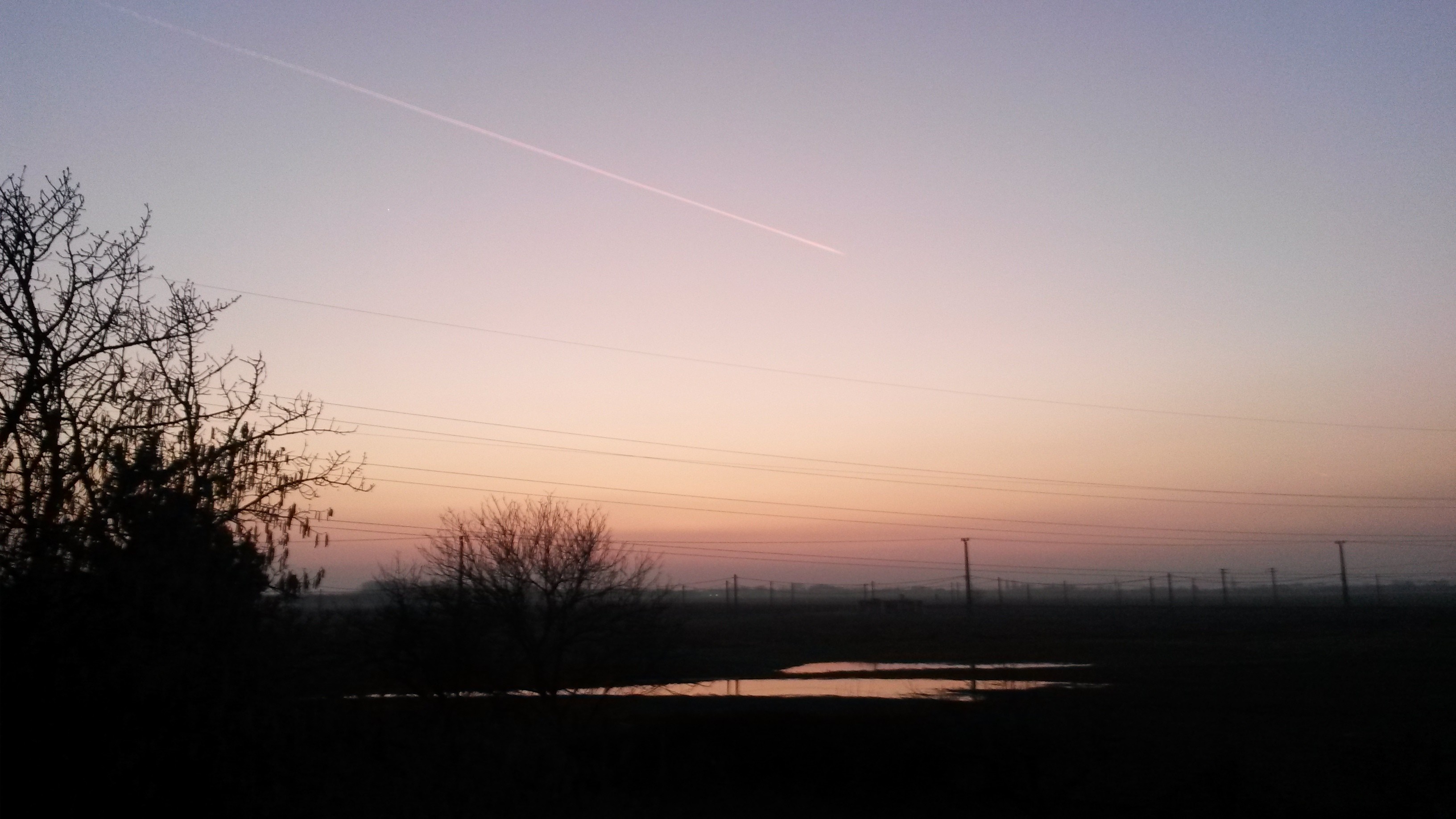 Sunset over a misty field with power lines HD Wallpaper