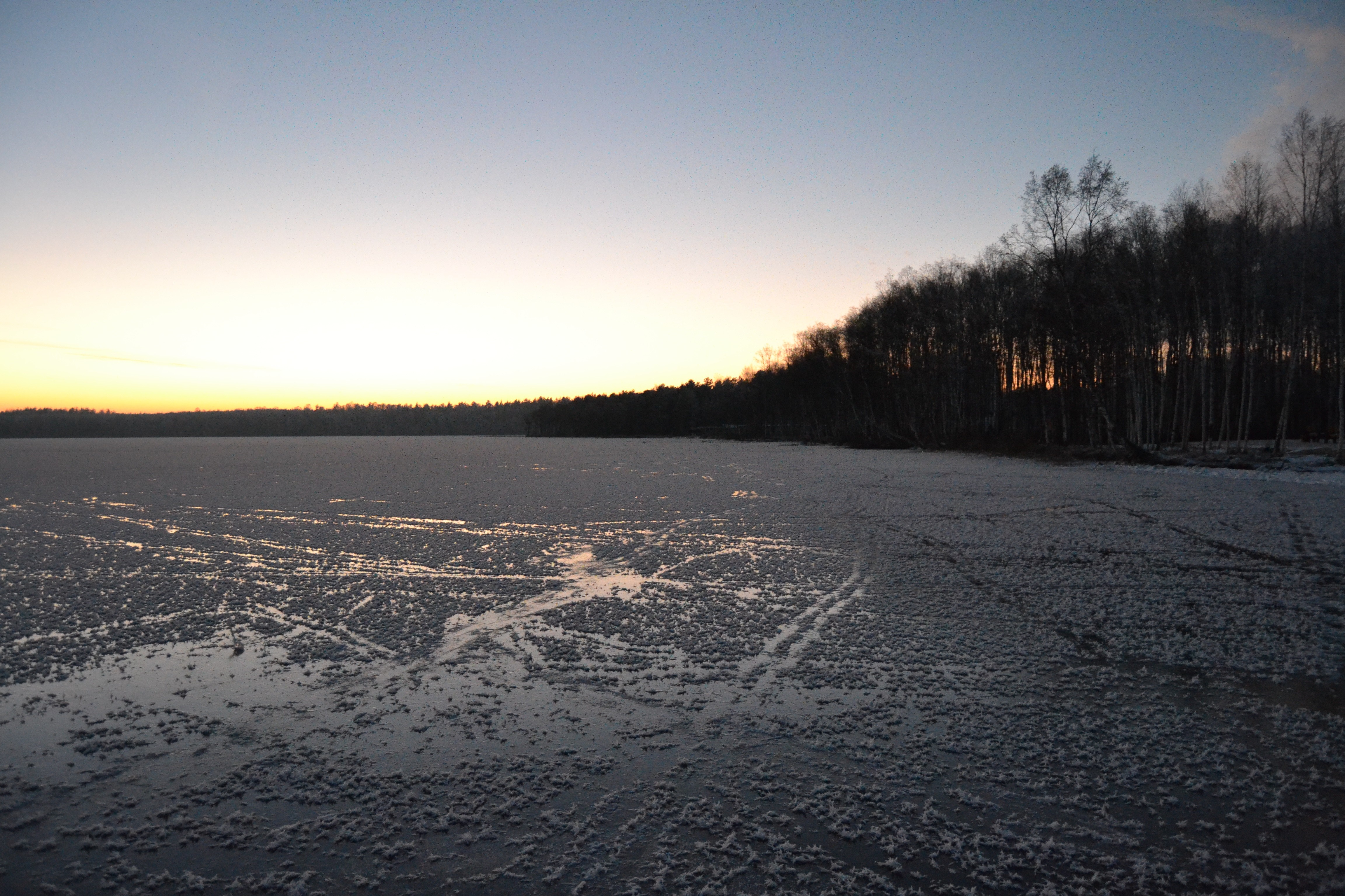 Frozen lake at sunset with trees on the horizon HD Wallpaper