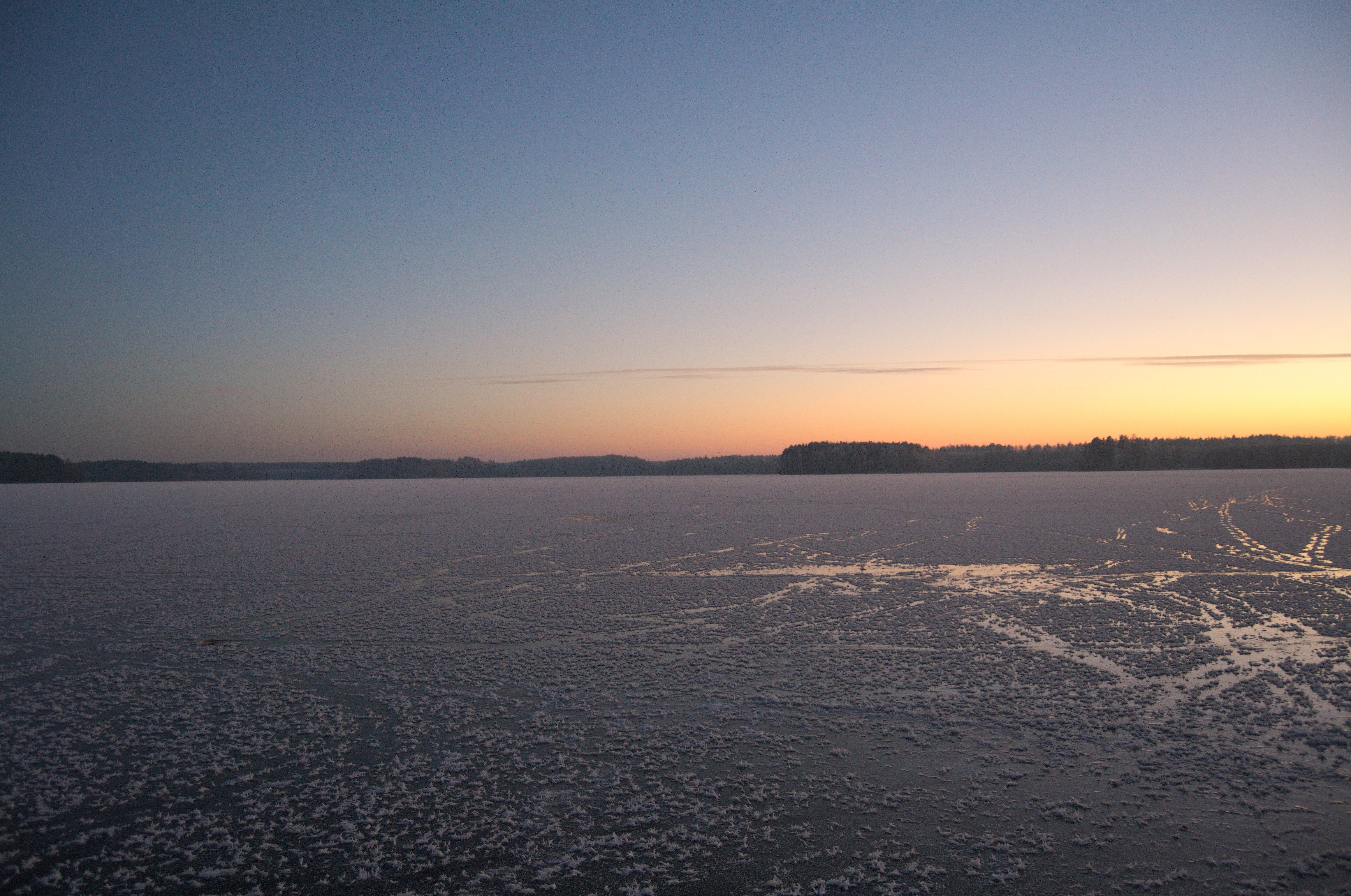 Frozen lake at sunset with distant treeline HD Wallpaper