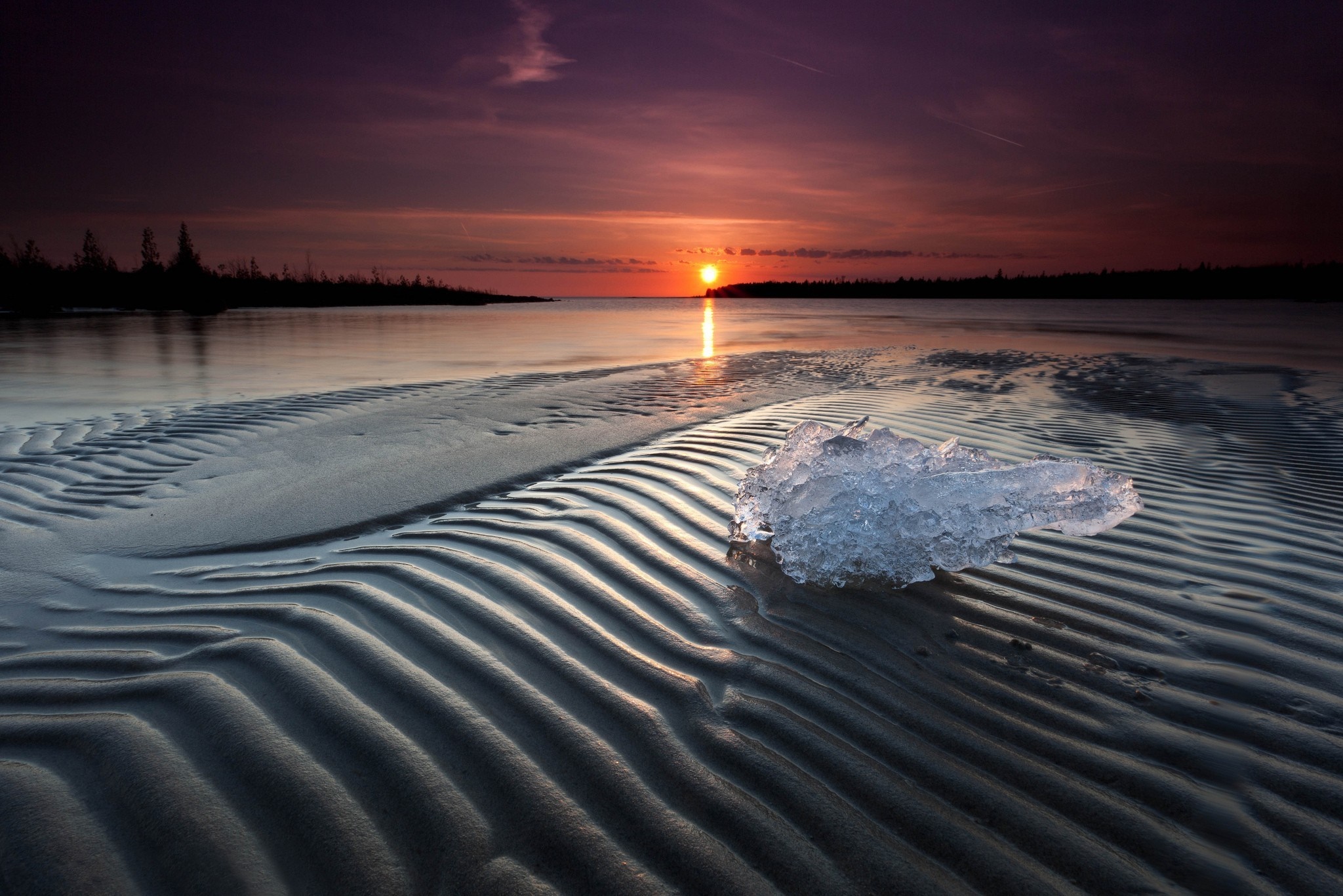 Ice on rippled sand at sunset over the ocean HD Wallpaper