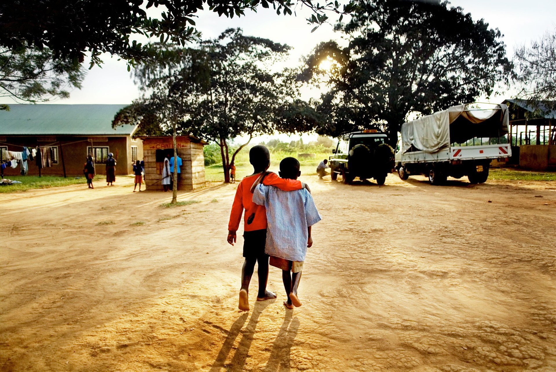 Two children walking with arms around each other in Africa HD Wallpaper