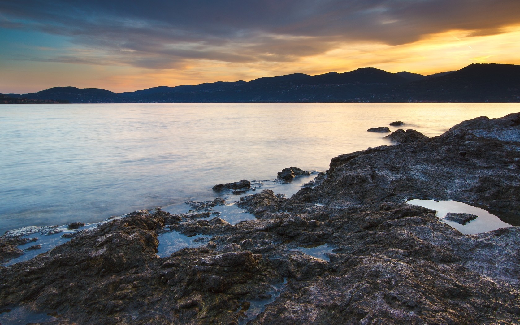 Rocky shore at sunset over the sea HD Wallpaper