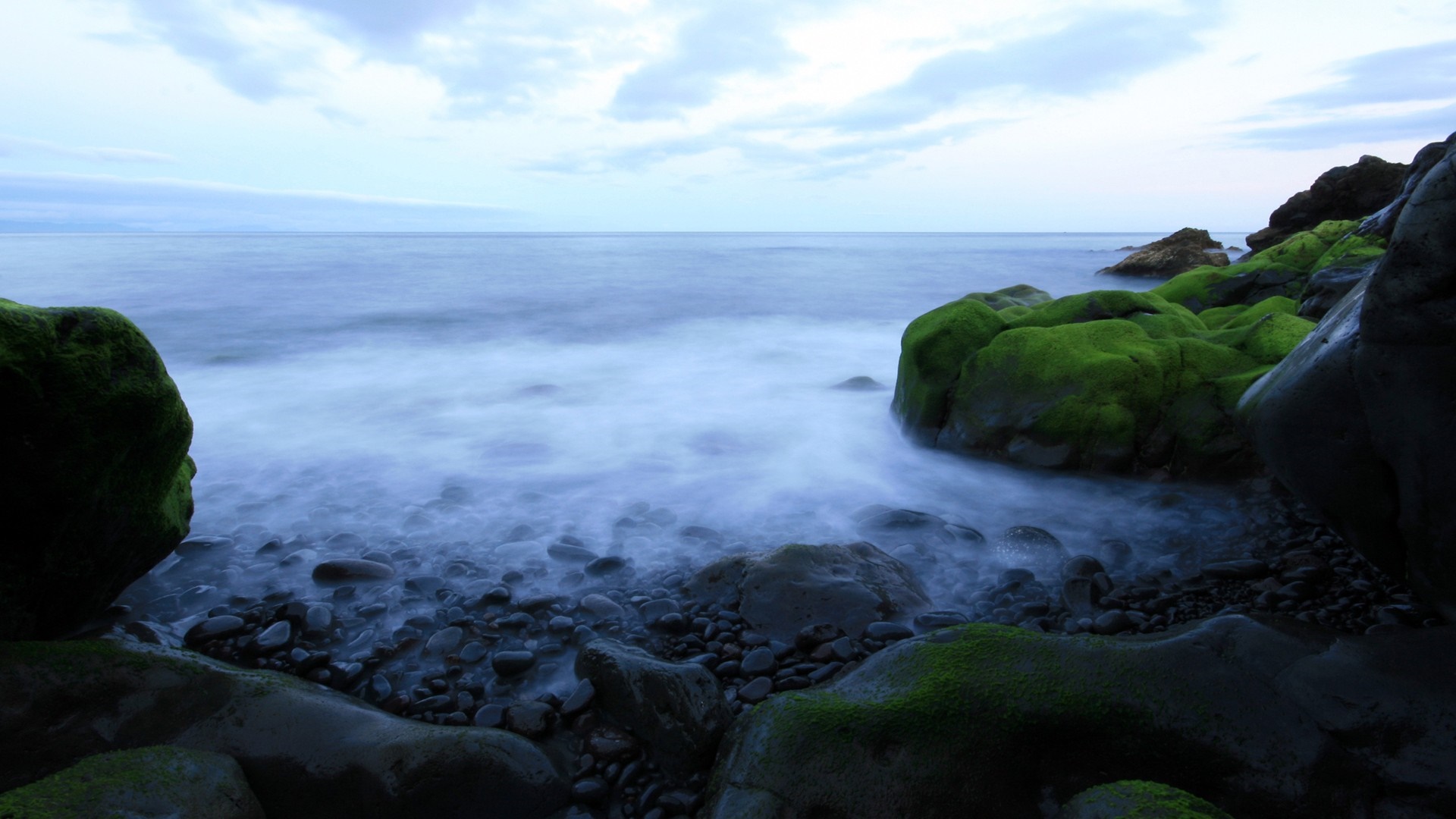 Mossy rocks on a rocky shore with ocean waves HD Wallpaper