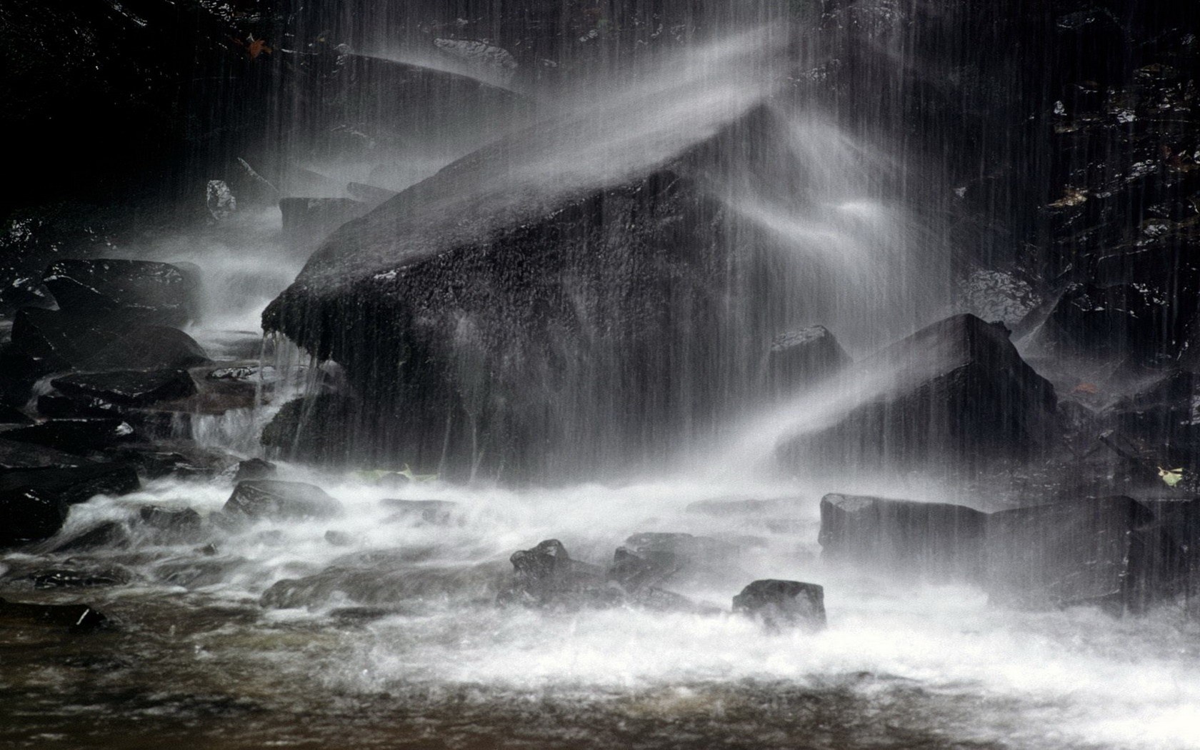 Monochrome waterfall cascading over dark rocks HD Wallpaper