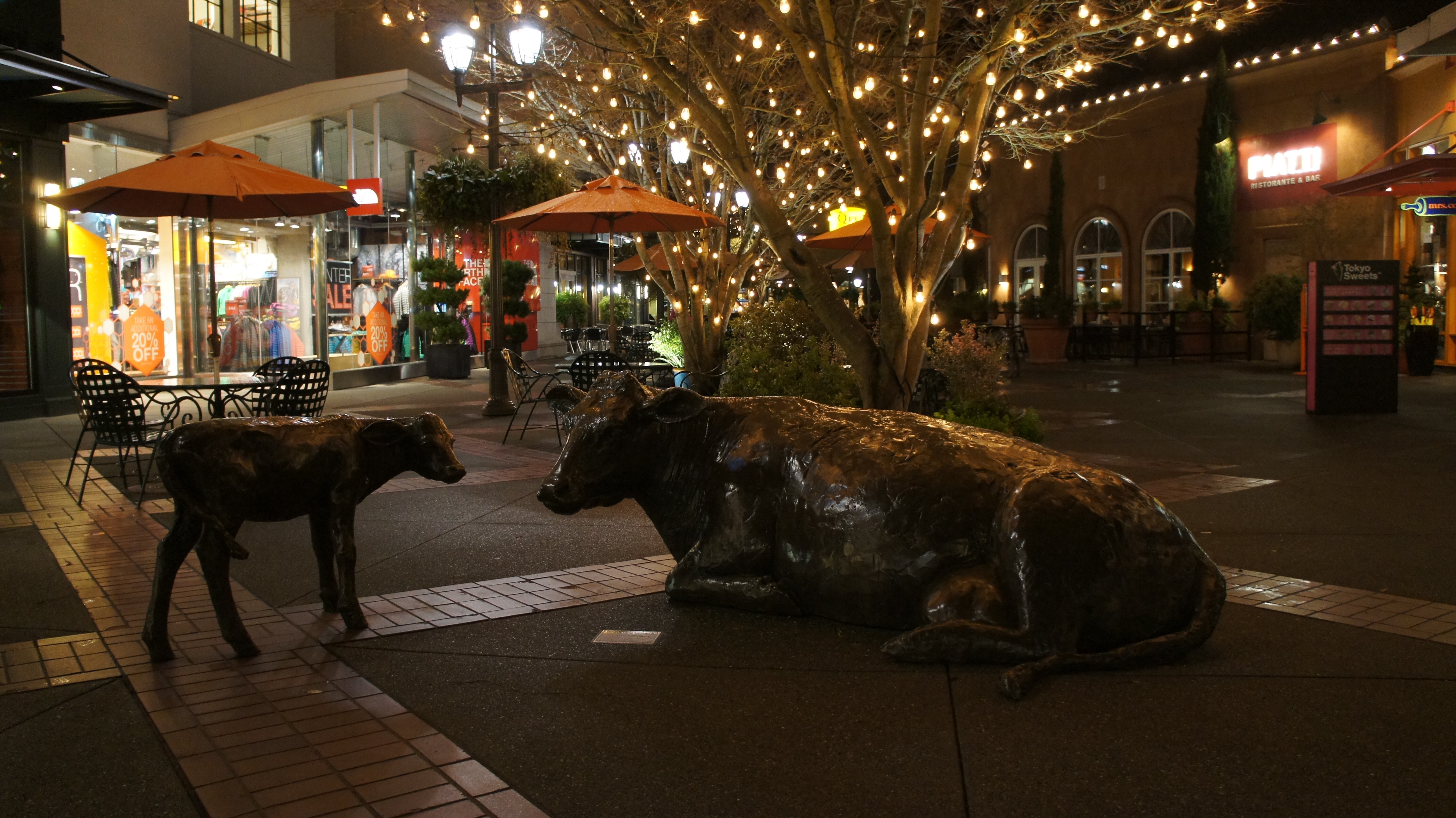 Cow and calf sculptures at night with string lights HD Wallpaper
