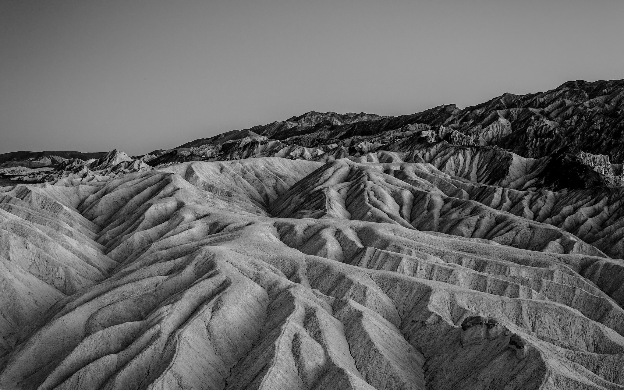 Monochrome landscape of eroded badlands under a clear sky HD Wallpaper