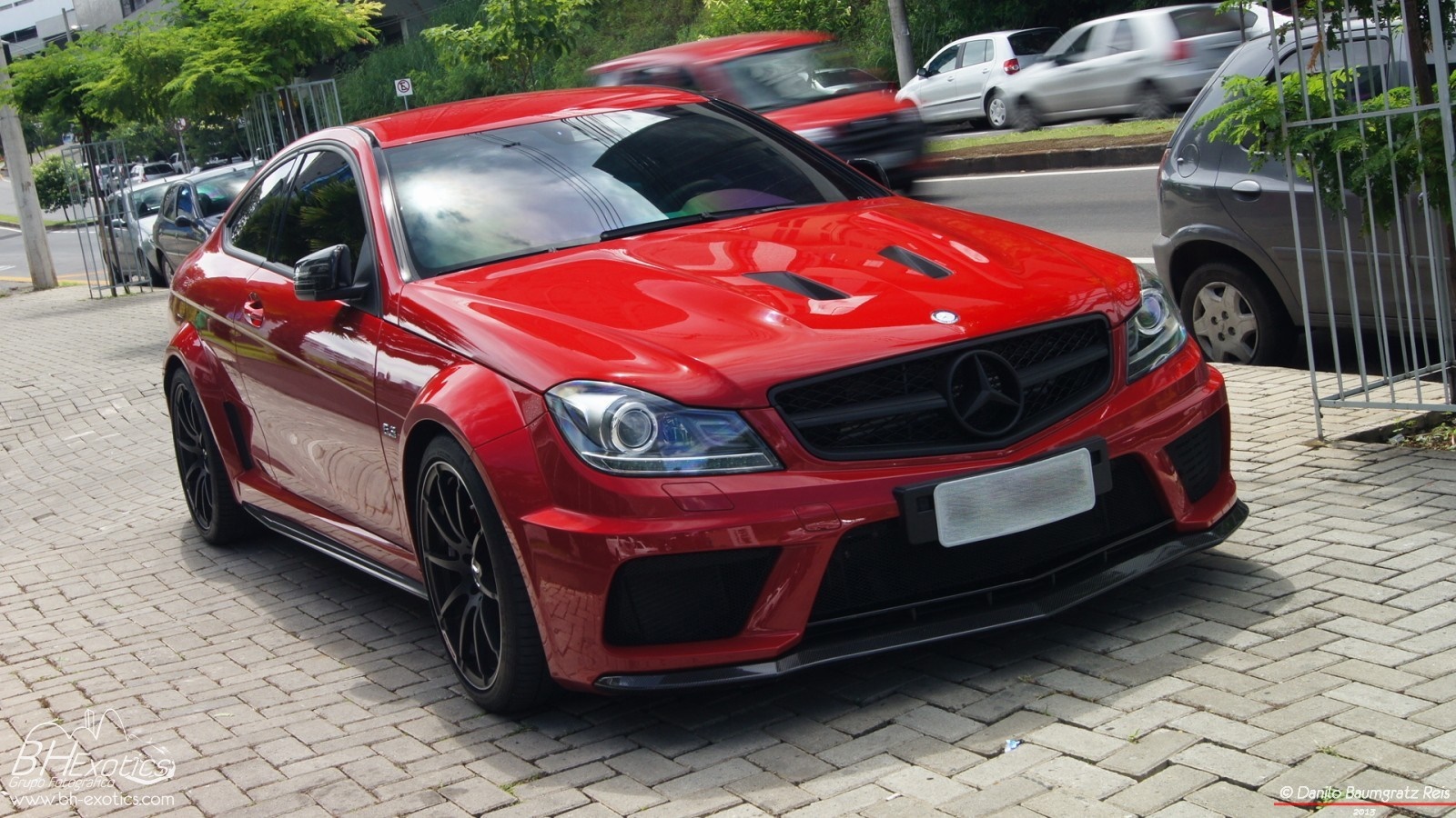 Red Mercedes-Benz C63 AMG Coupe parked on a brick sidewalk HD Wallpaper