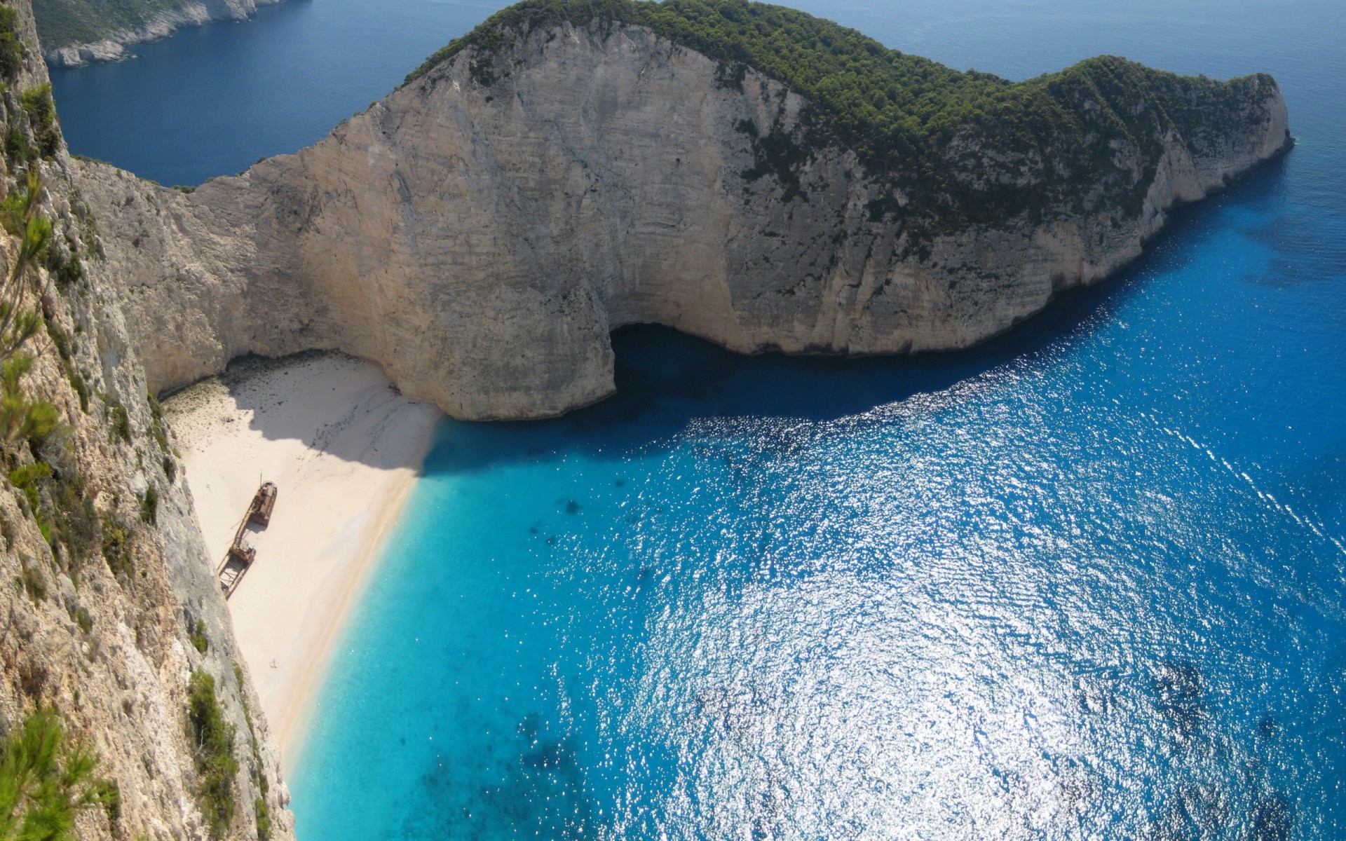 Shipwreck beach on a rocky island with blue ocean HD Wallpaper