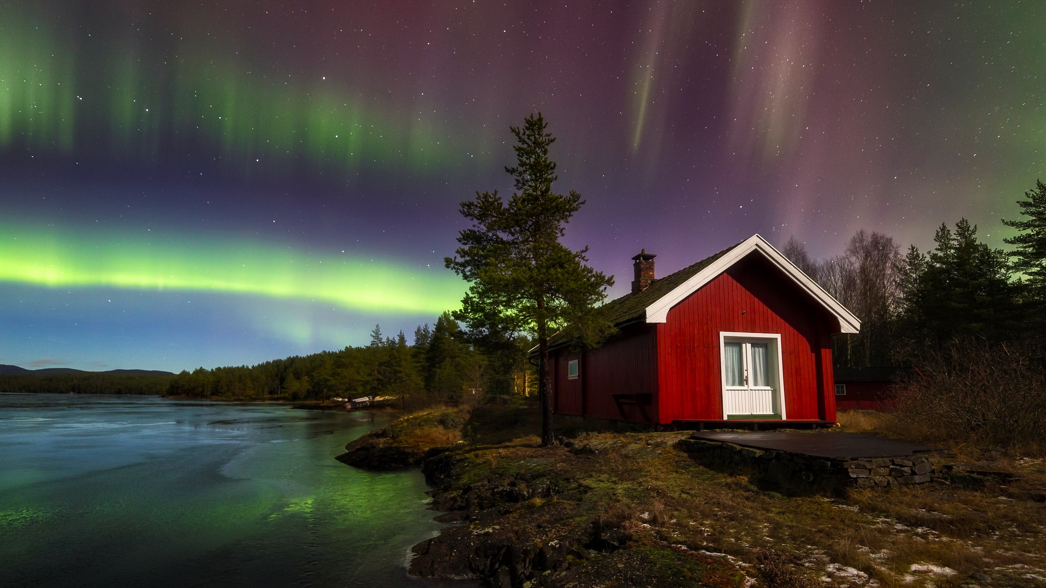 Red cabin under the Aurora Borealis by a lake HD Wallpaper