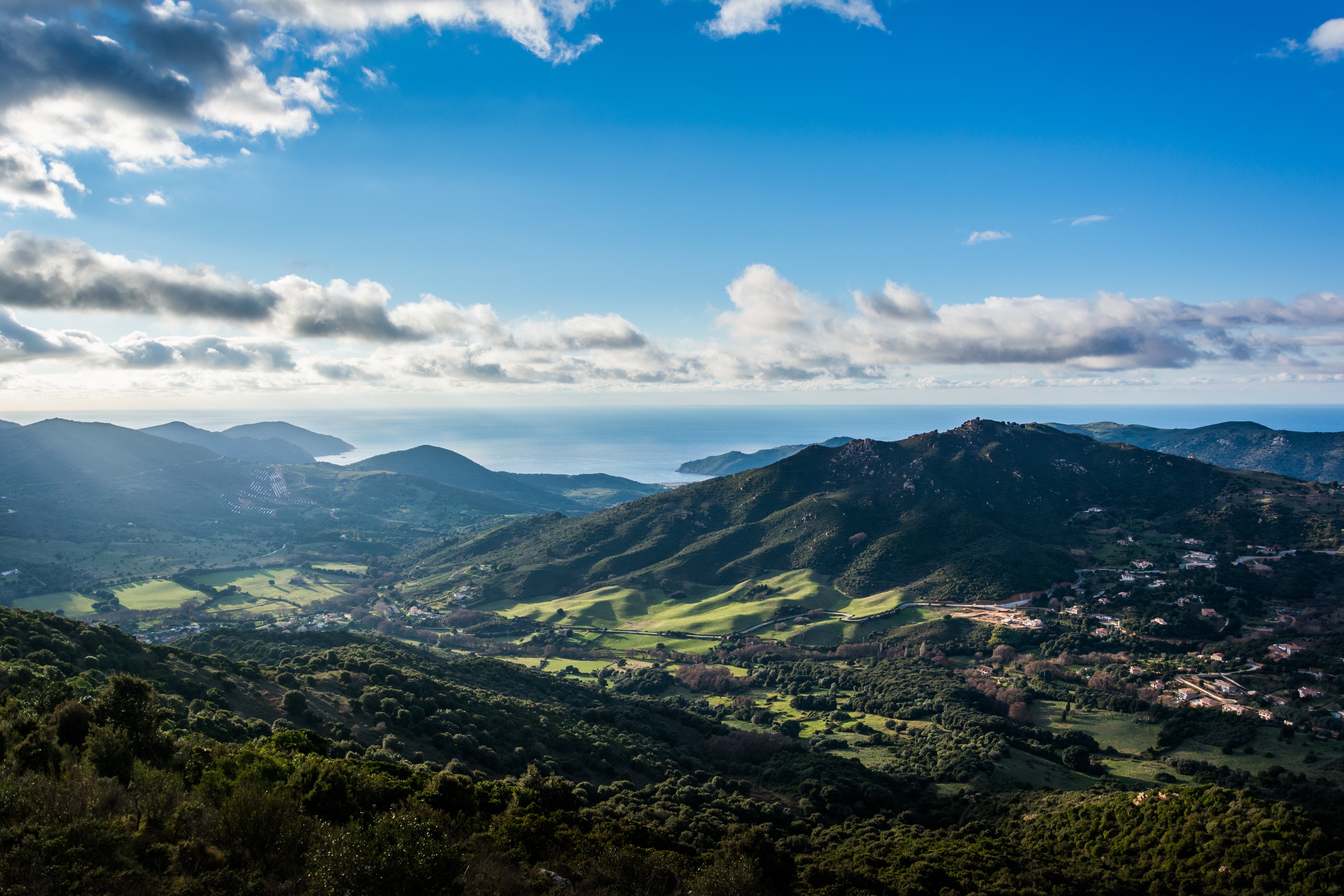 Sunlit valley and hills overlooking the sea HD Wallpaper