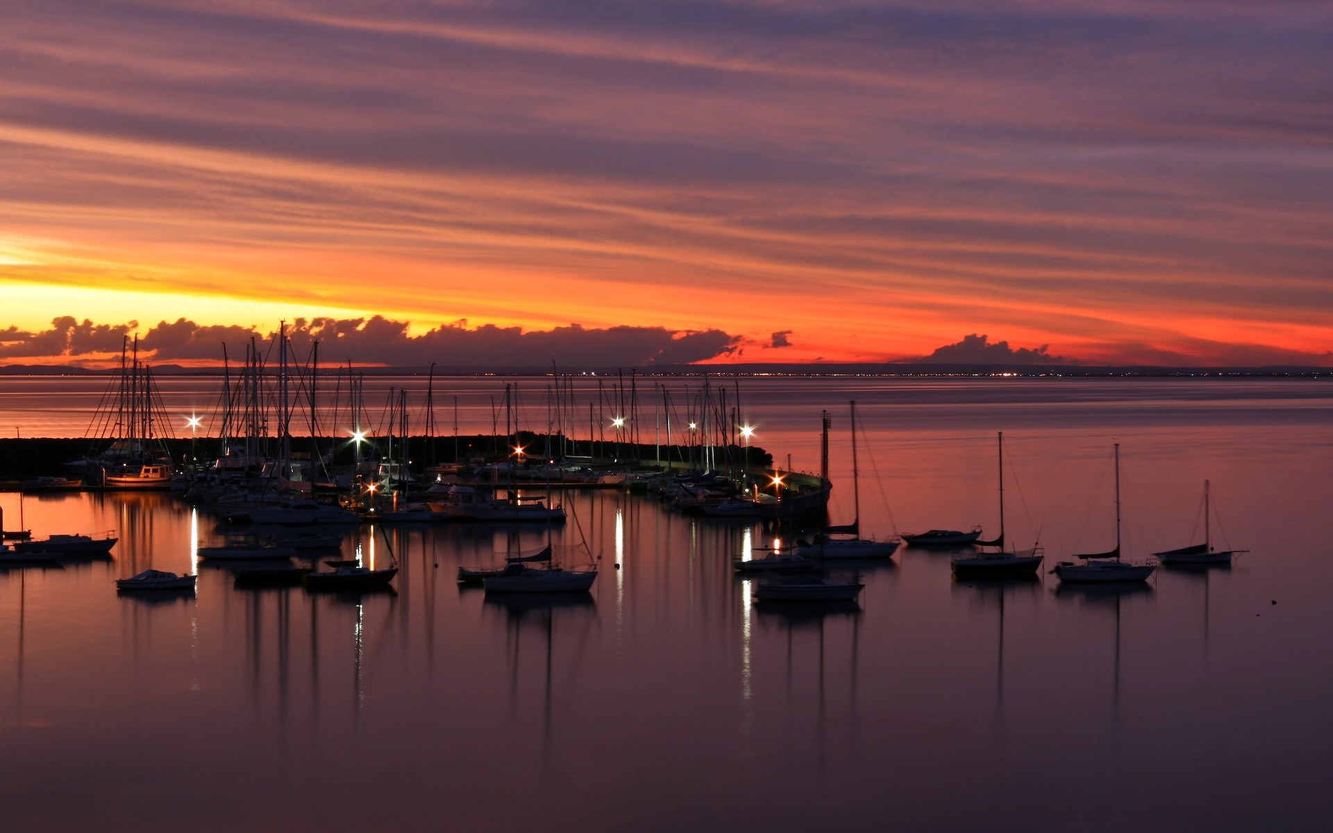 Boats docked at a marina during a colorful sunset over the water HD Wallpaper