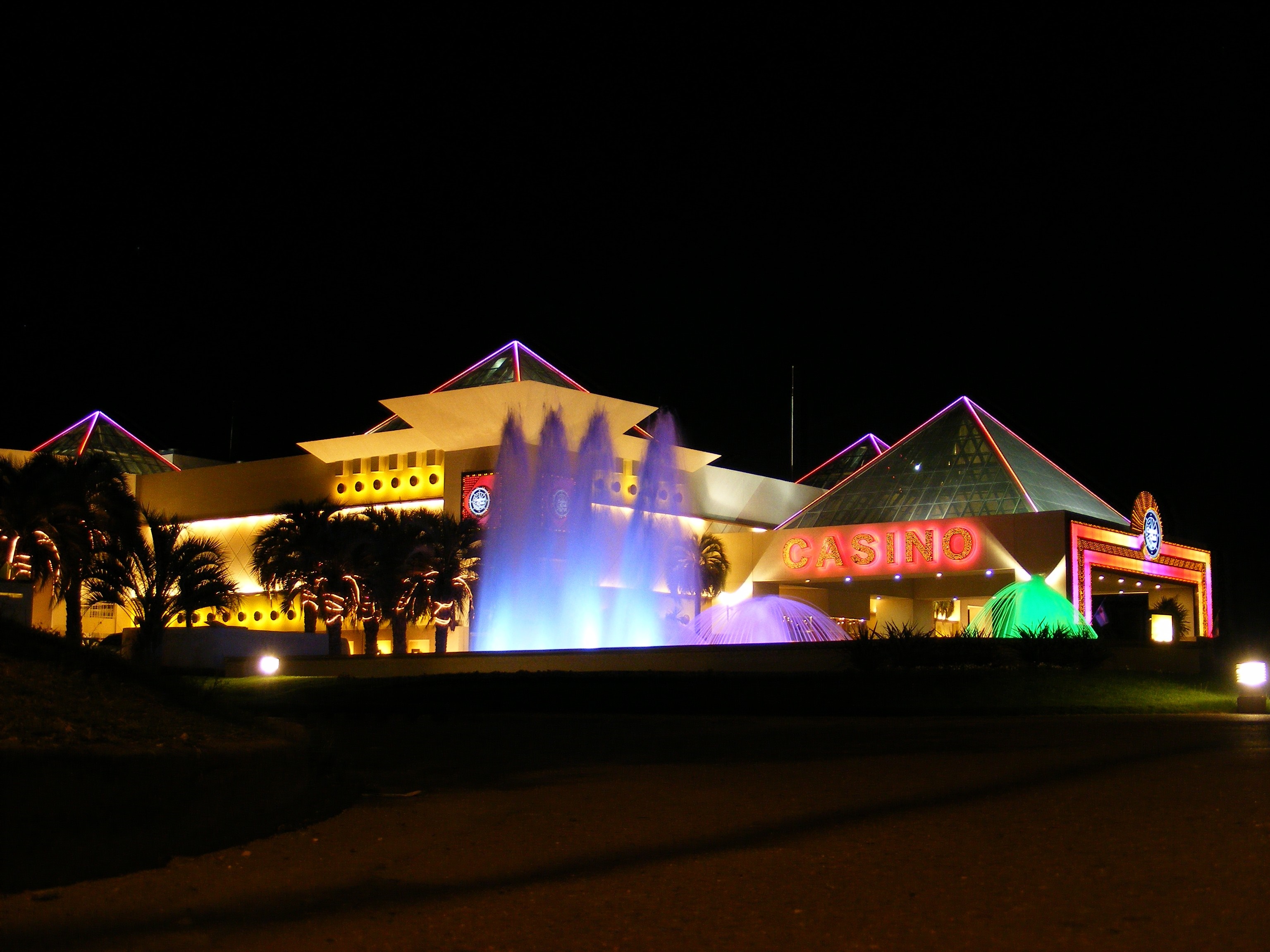 Casino building with fountains and palm trees at night HD Wallpaper