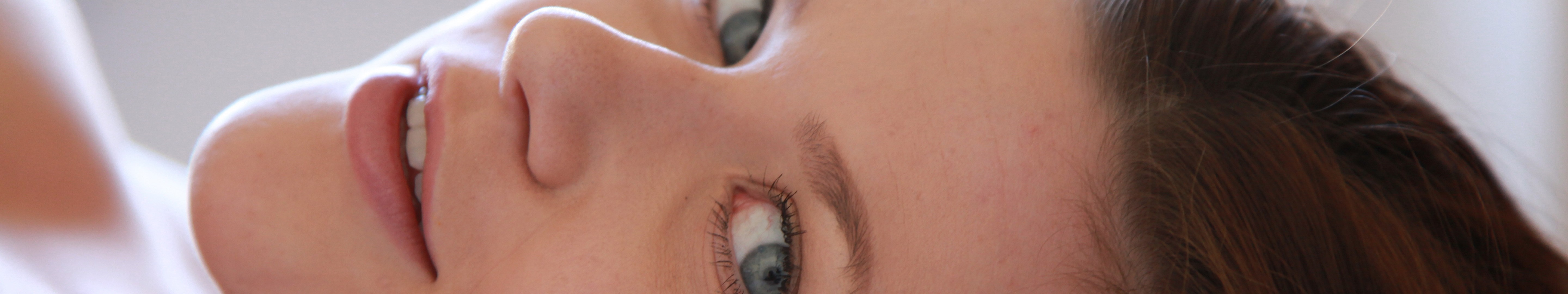 Close-up of a woman's face with blue eyes and brown hair HD Wallpaper