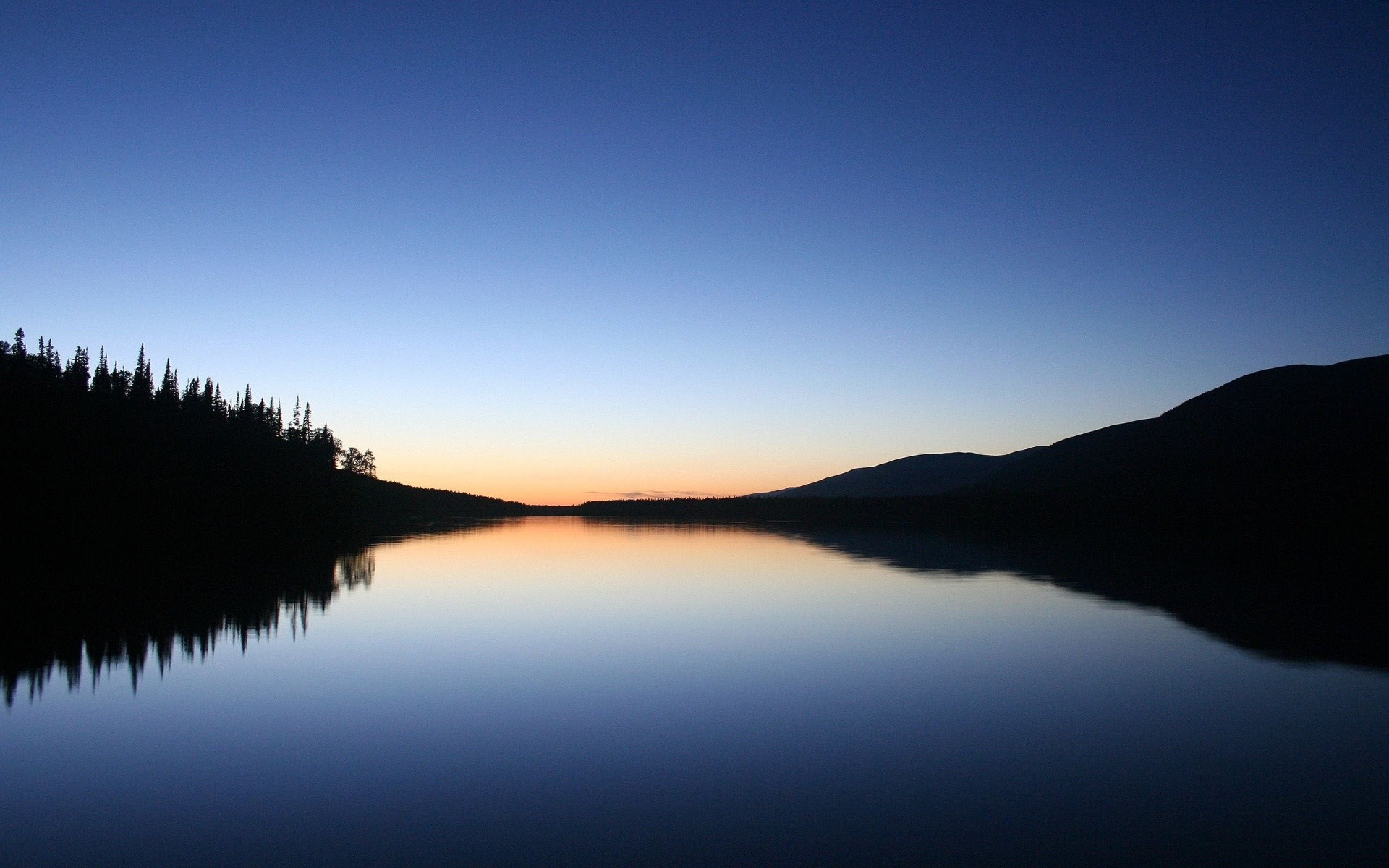 Lake reflection at dusk with silhouetted trees and mountains HD Wallpaper