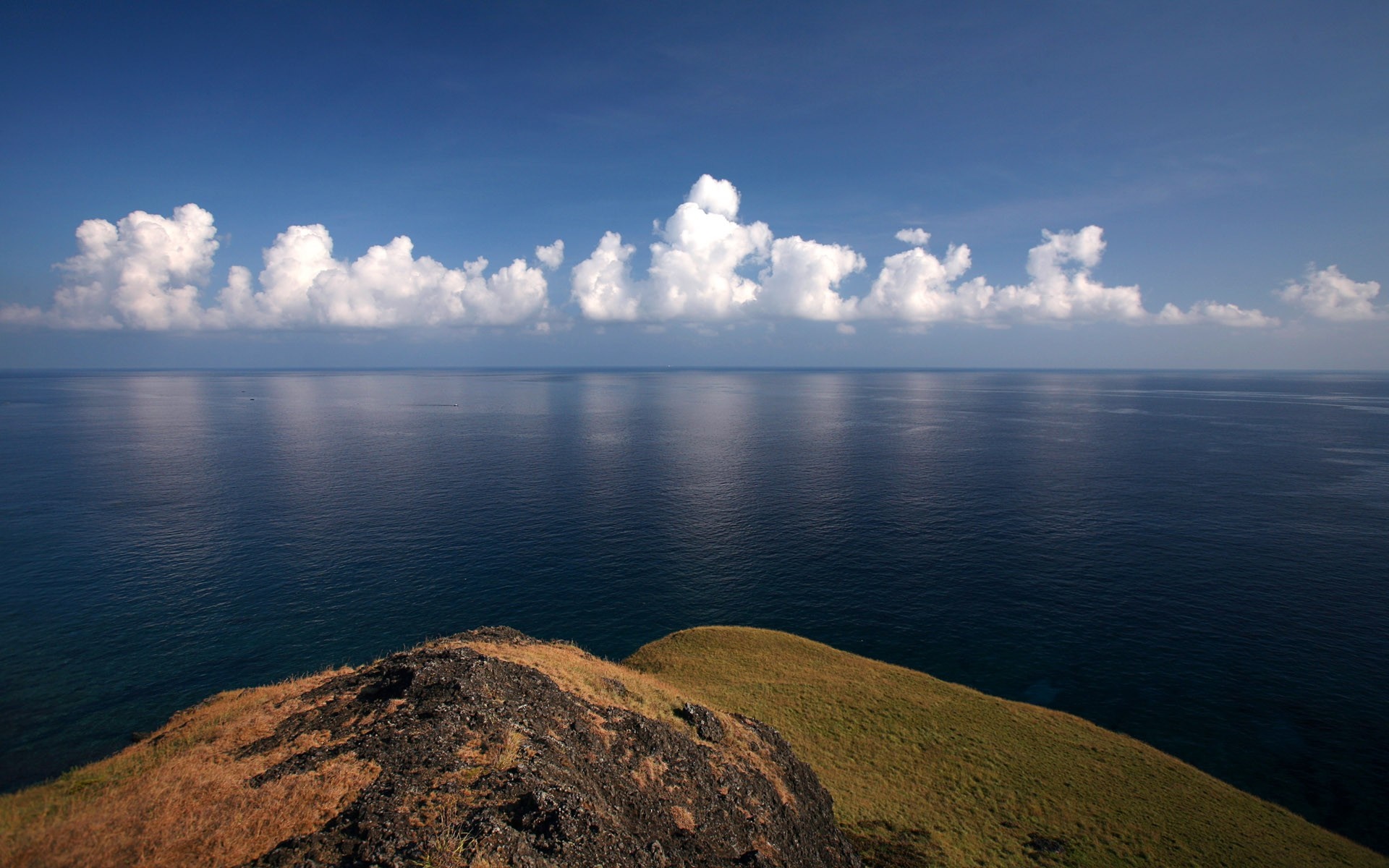 Ocean horizon with clouds over a grassy cliff HD Wallpaper