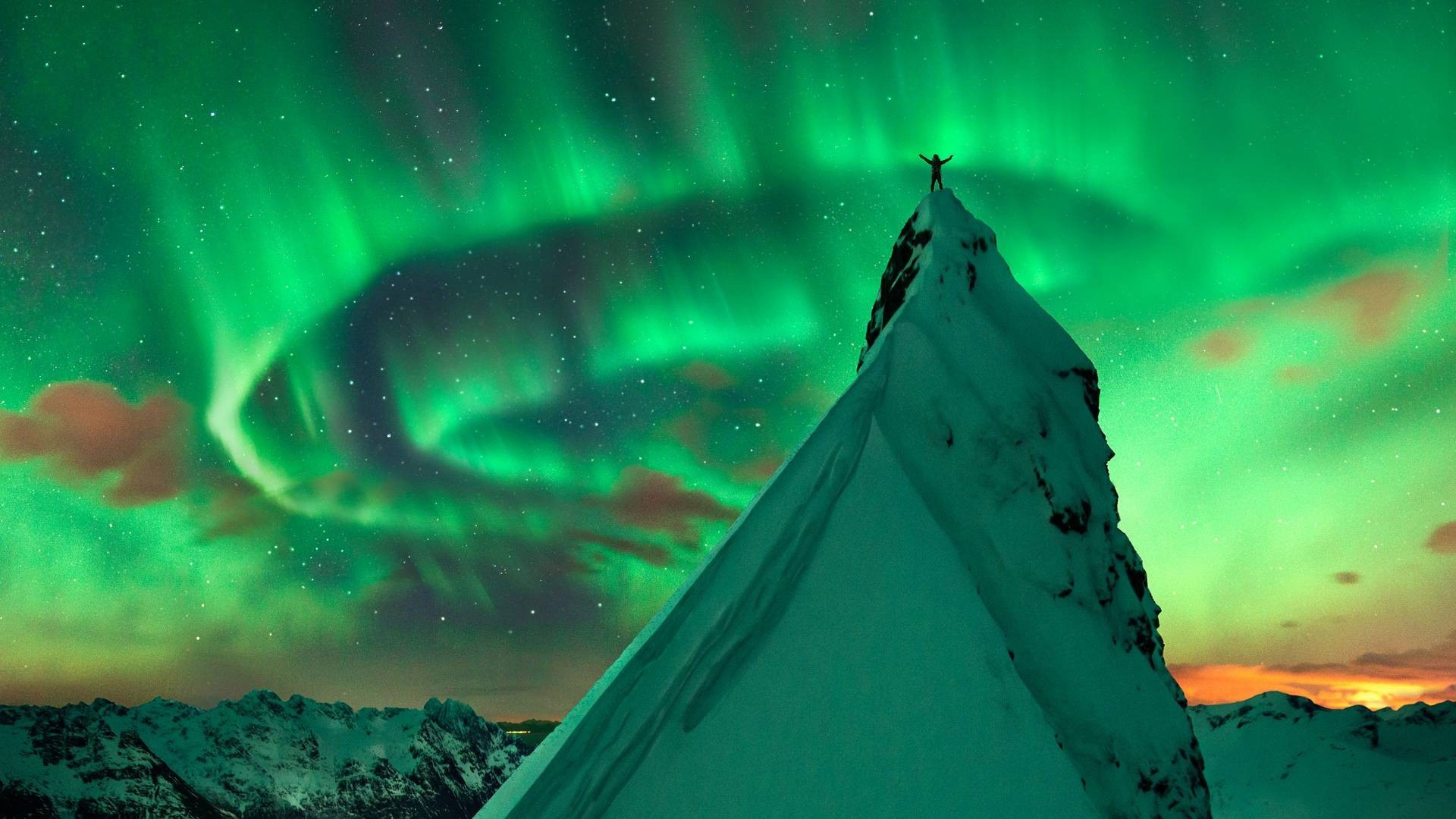 Person on mountain peak under aurora borealis HD Wallpaper