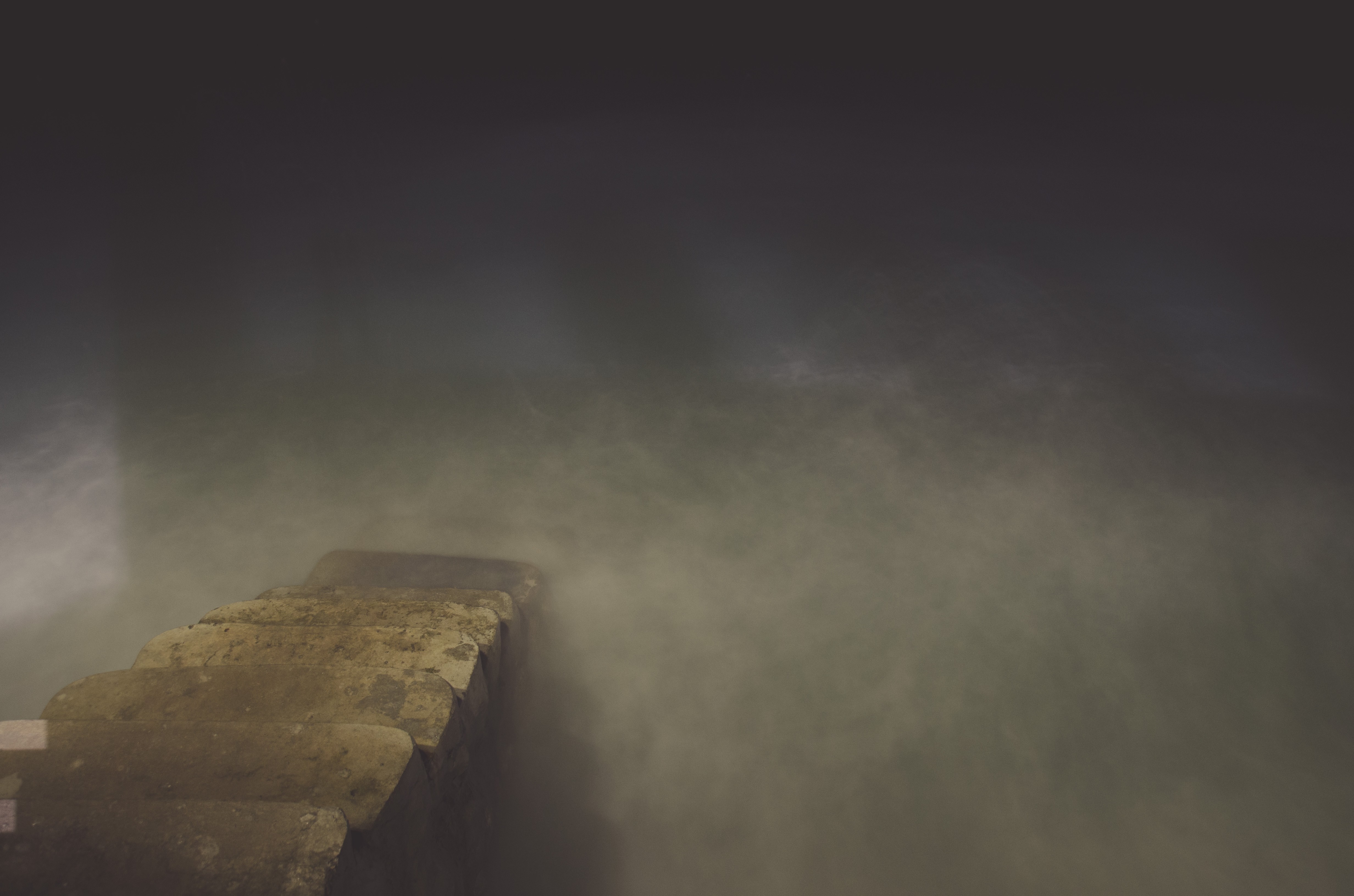 Stone stairs leading into misty water at night HD Wallpaper