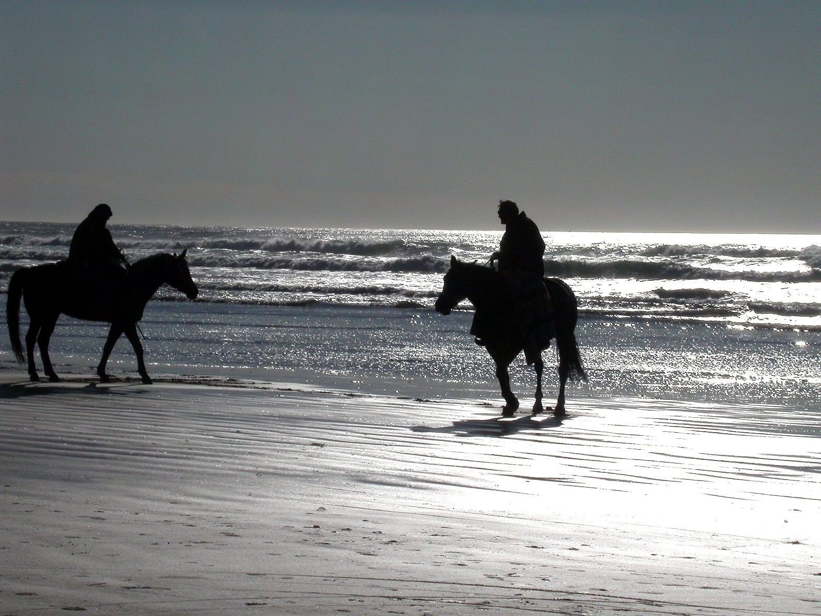 Two people on horseback on a beach with waves HD Wallpaper