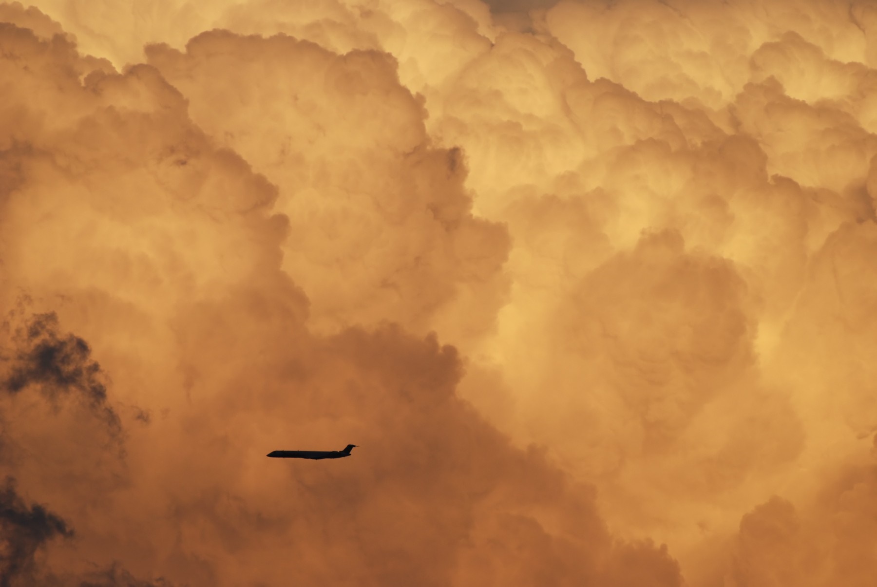 Airplane flying through dramatic sunset clouds HD Wallpaper