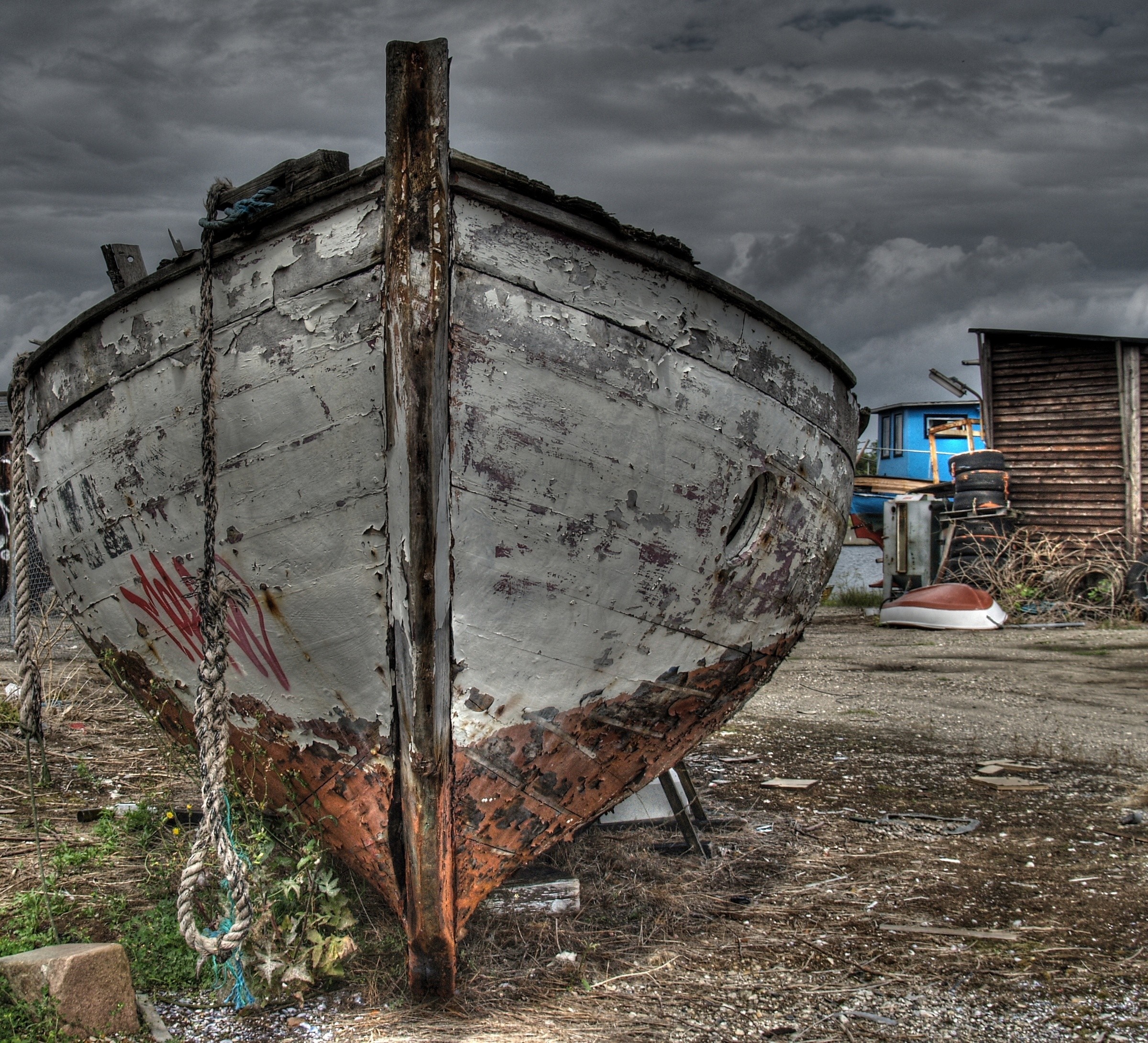 Abandoned wooden boat on shore with stormy sky HD Wallpaper