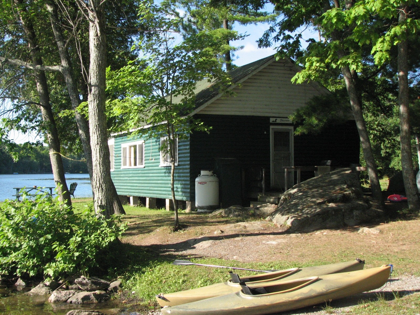 Green cabin by a lake with kayaks HD Wallpaper