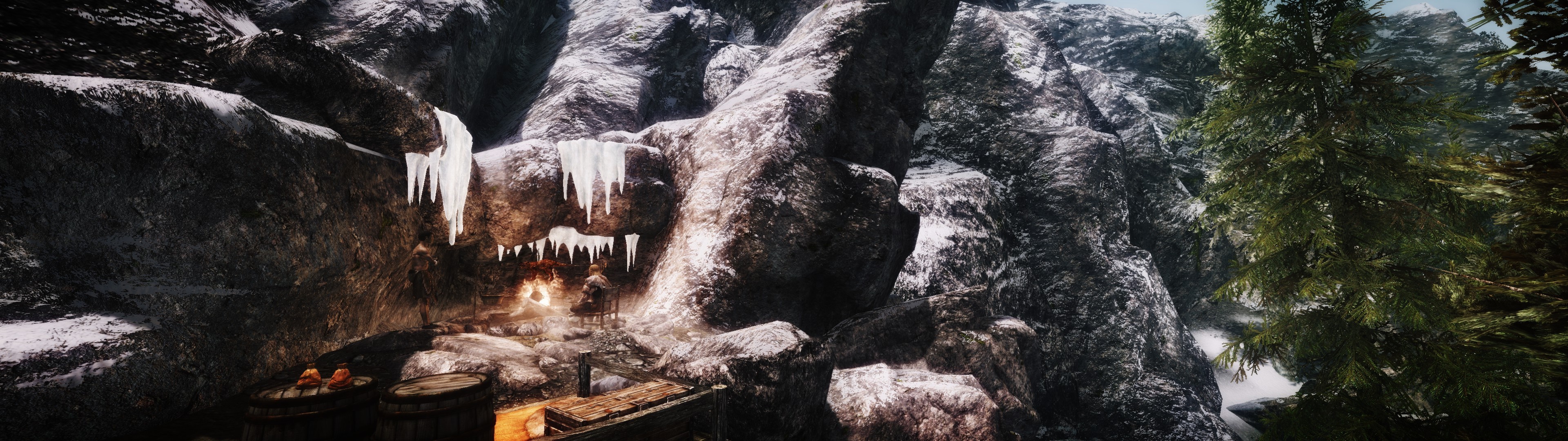 Cave entrance with icicles and a campfire in a snowy mountain landscape HD Wallpaper