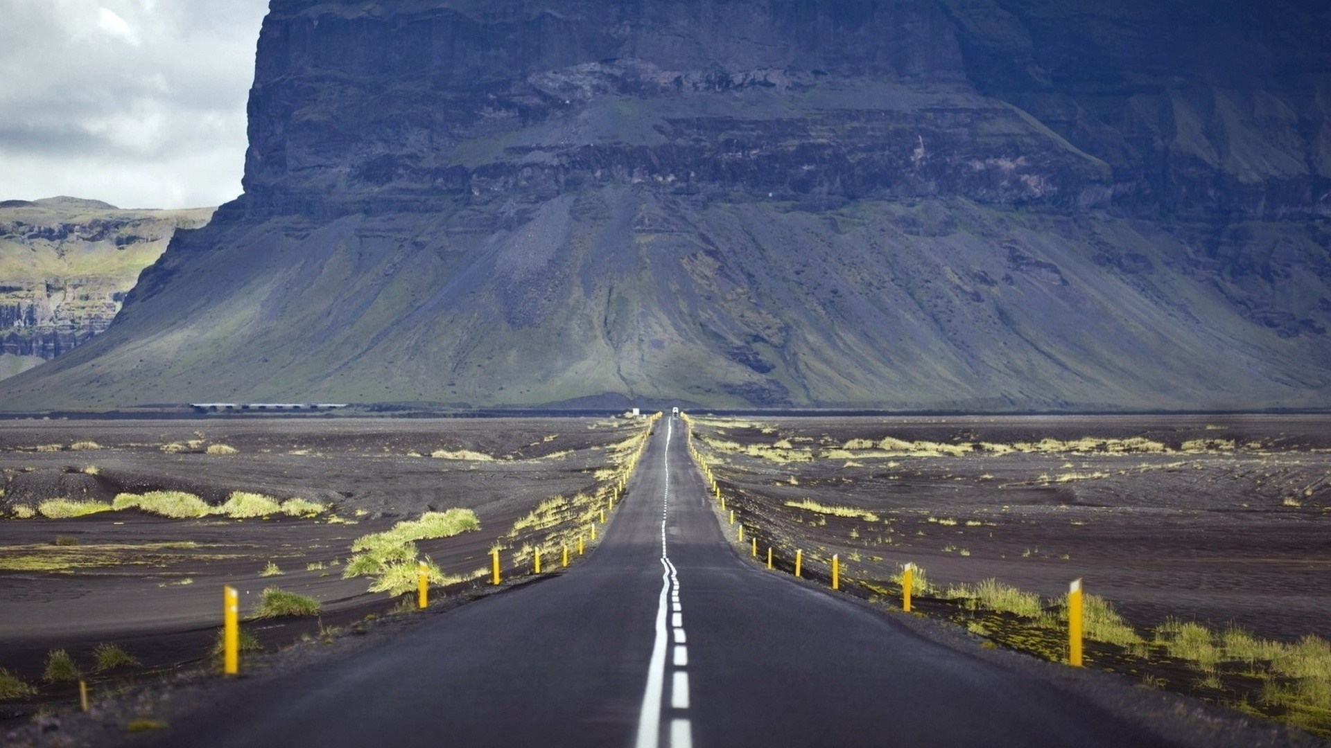Road leading to a large mountain in a barren landscape HD Wallpaper