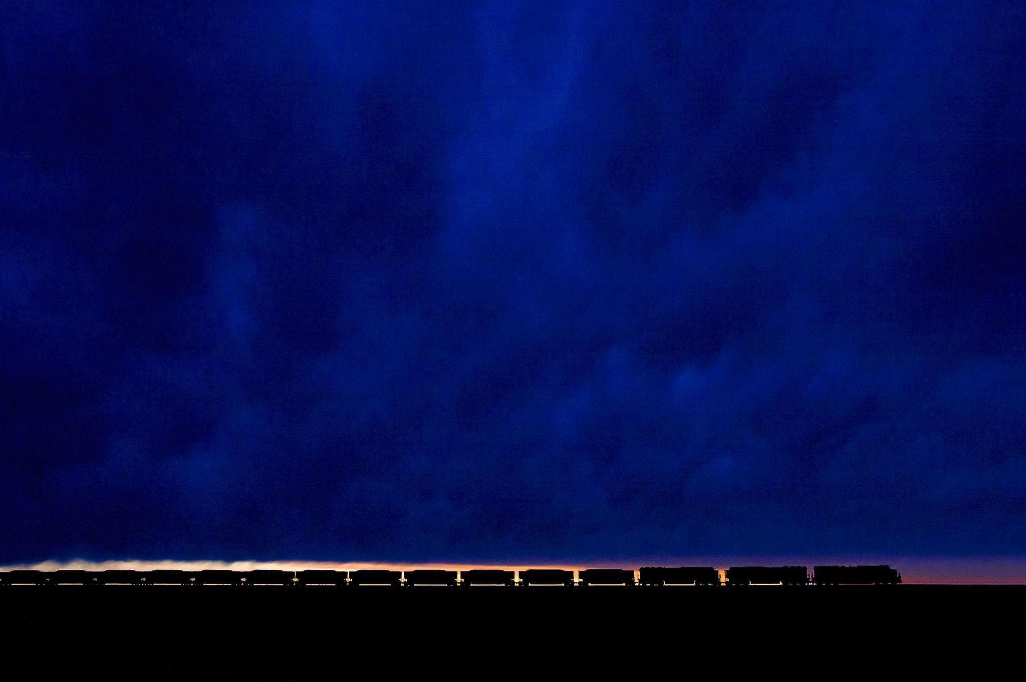 Train silhouette against a dark blue cloudy sky at dusk HD Wallpaper