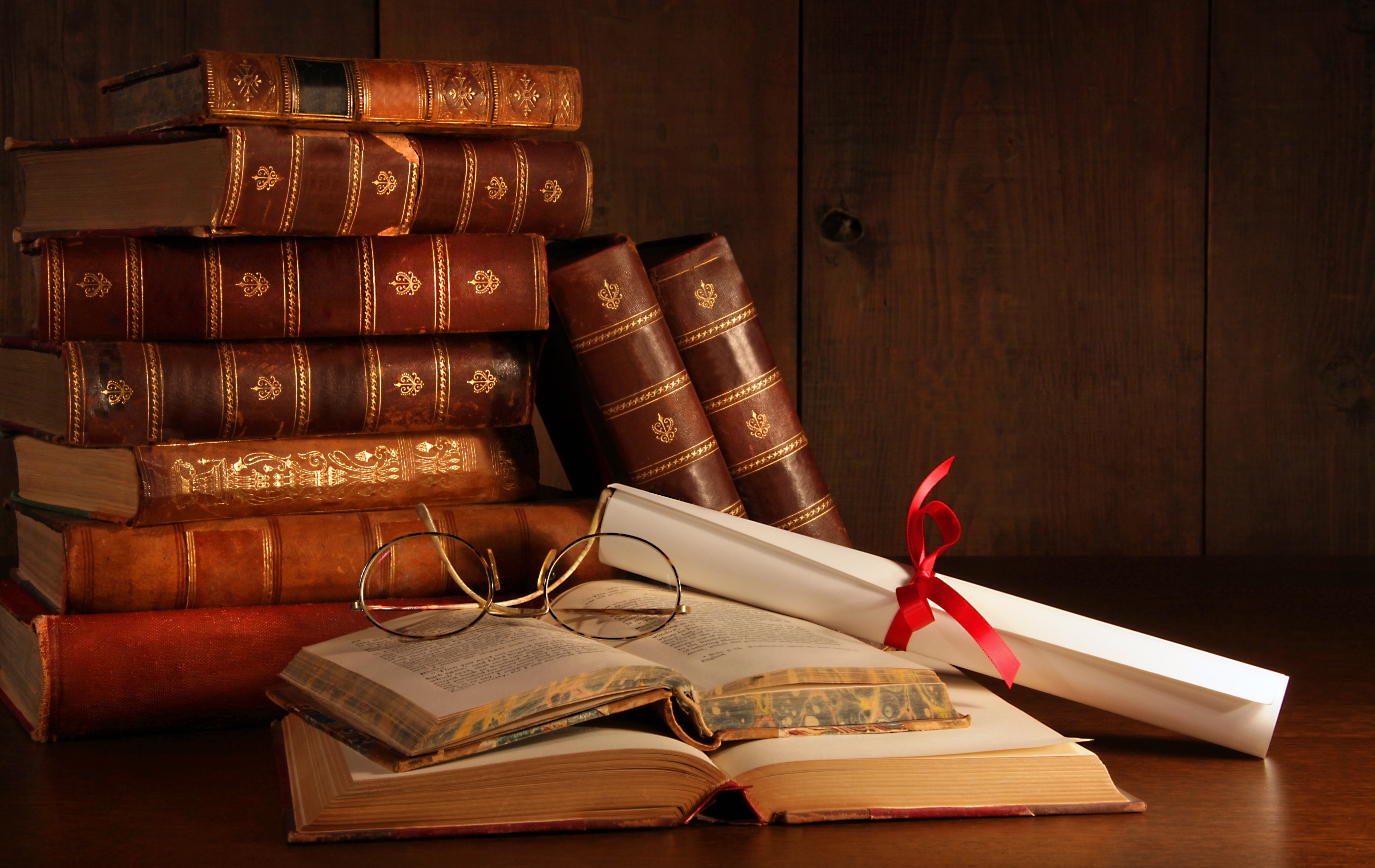 Stack of antique books with glasses and diploma HD Wallpaper