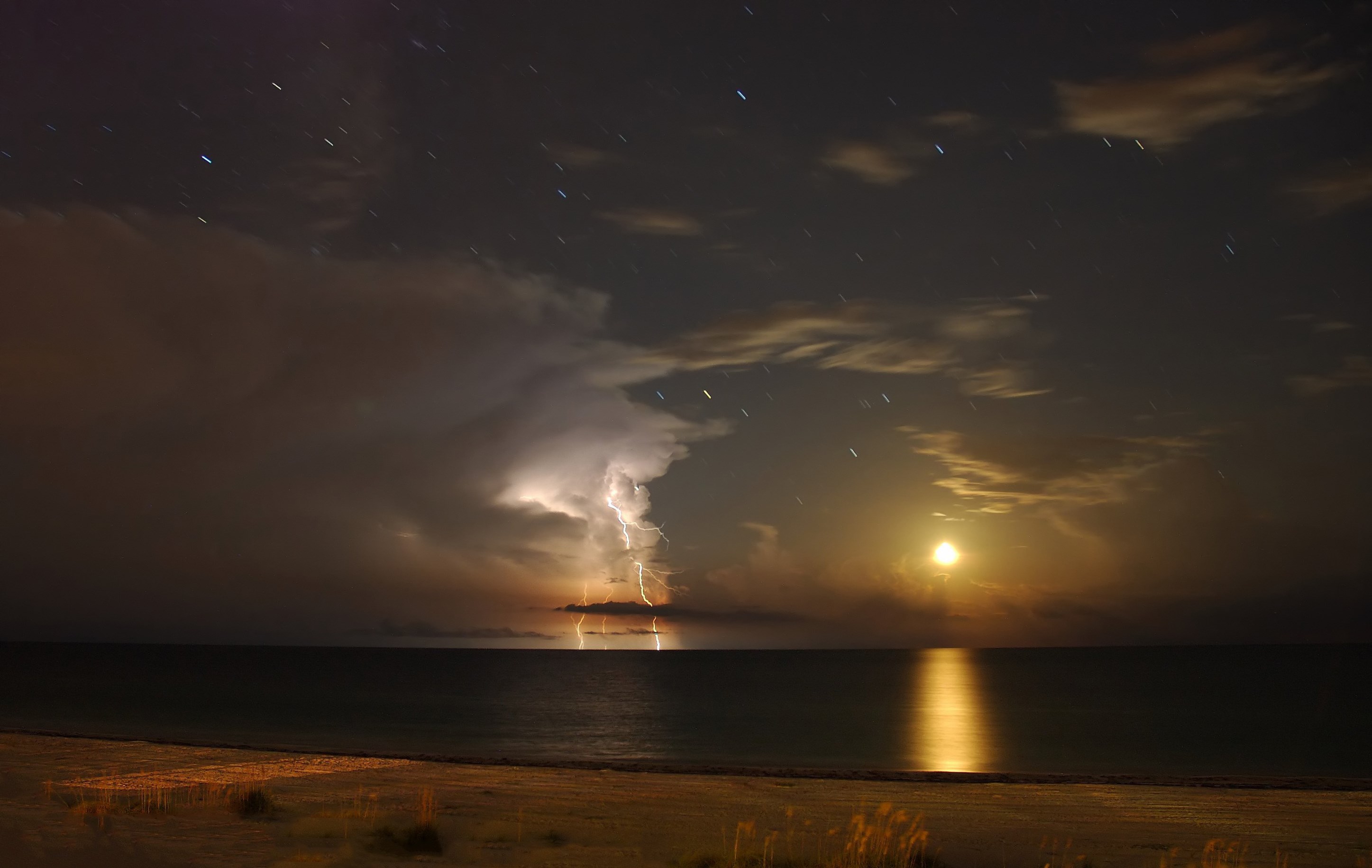 Lightning strikes over the ocean at night with moon HD Wallpaper
